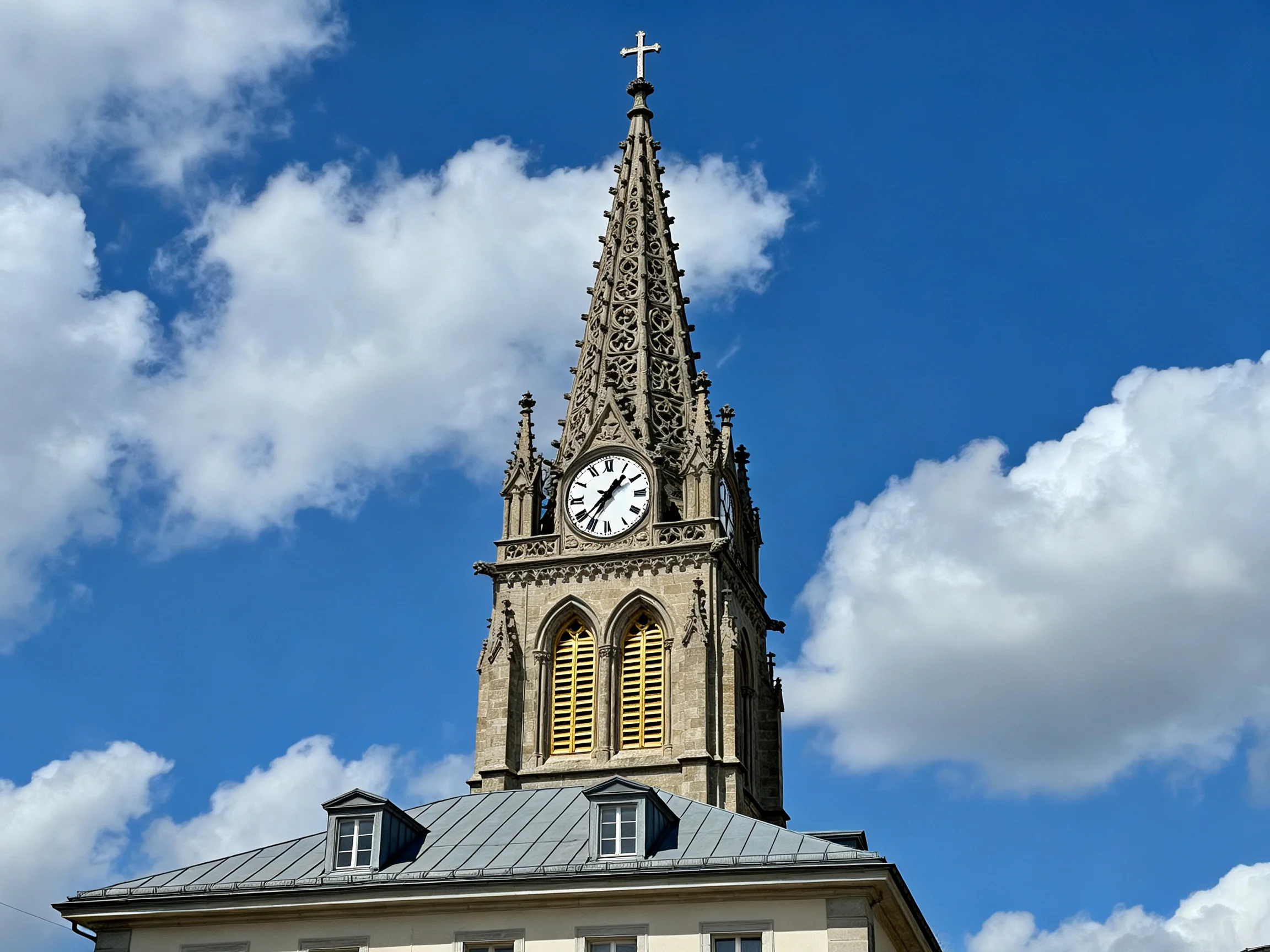 Ornate Gothic clock tower with spire against blue sky