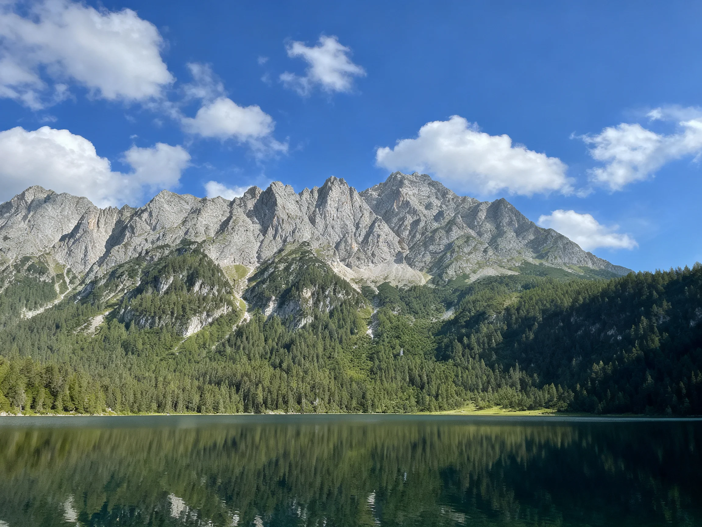 Rugged Mountain Peaks Reflecting in a Calm Lake Under Clear Blue Sky
