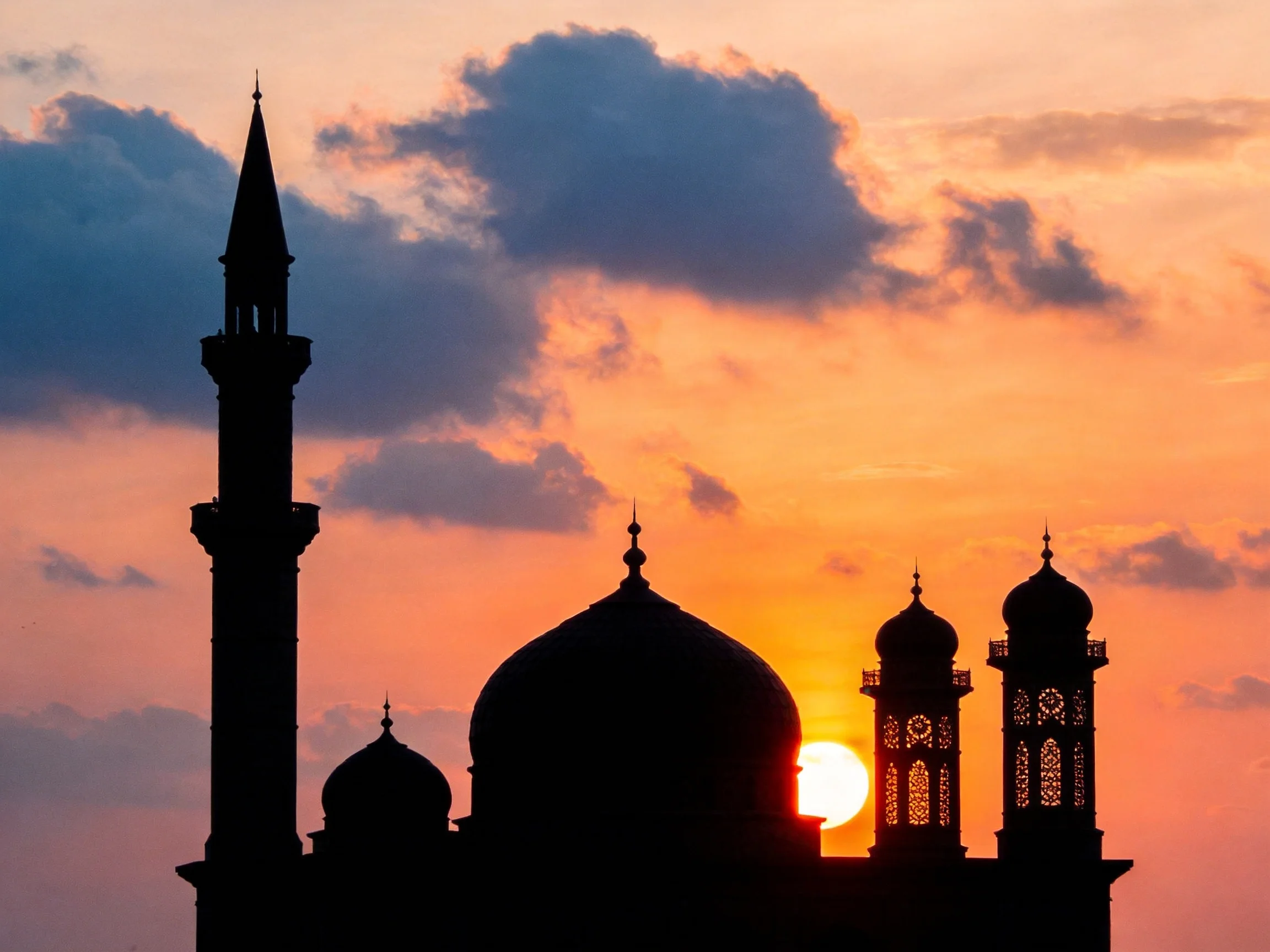 Silhouetted Mosque with Domes and Minarets Under Vibrant Sunset