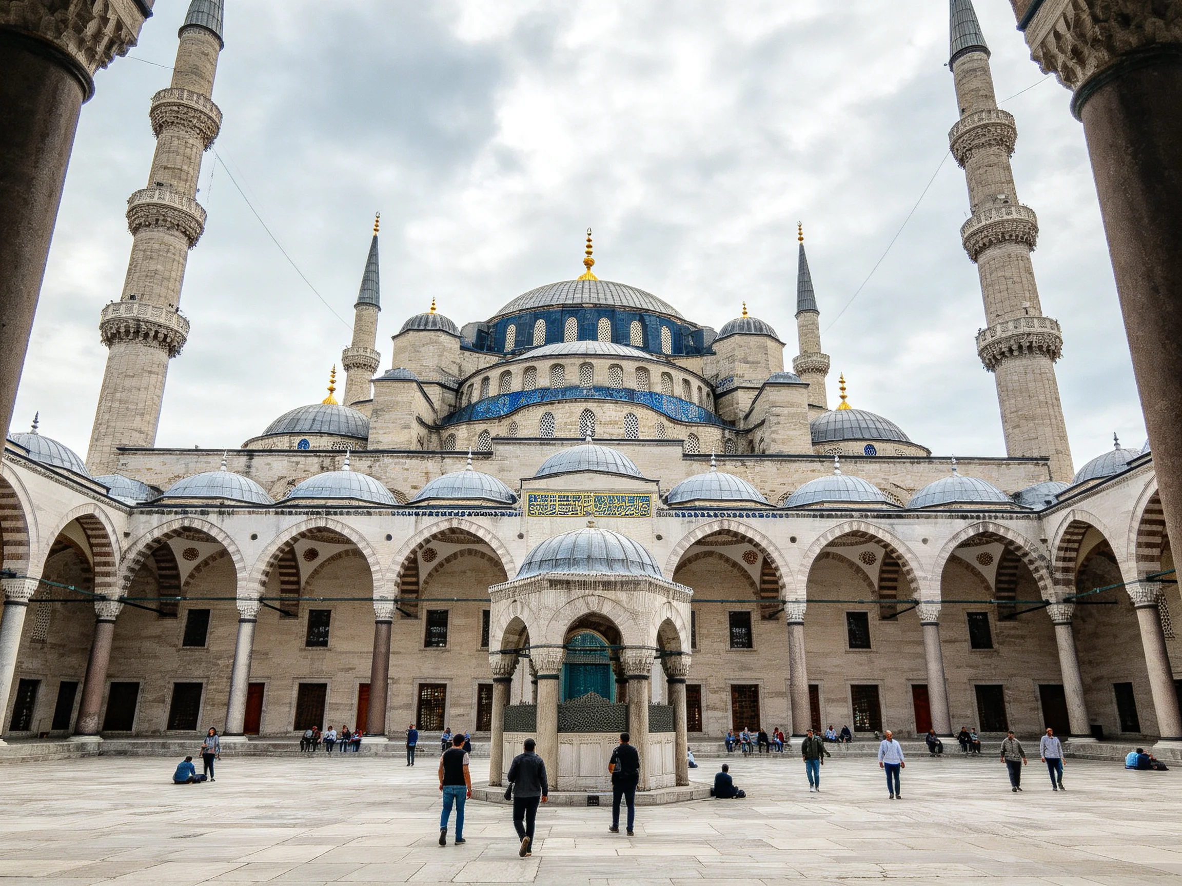 Six minarets rise beside domed stone mosque with blue accents
