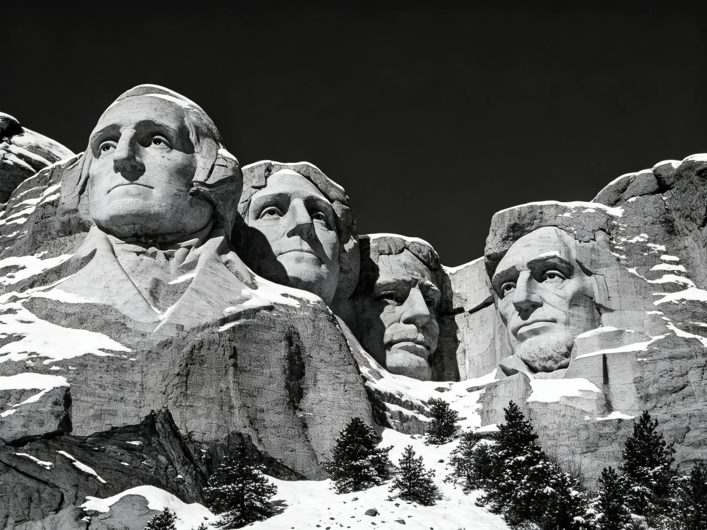 Snow-capped Mount Rushmore sculptures with pine trees in foreground