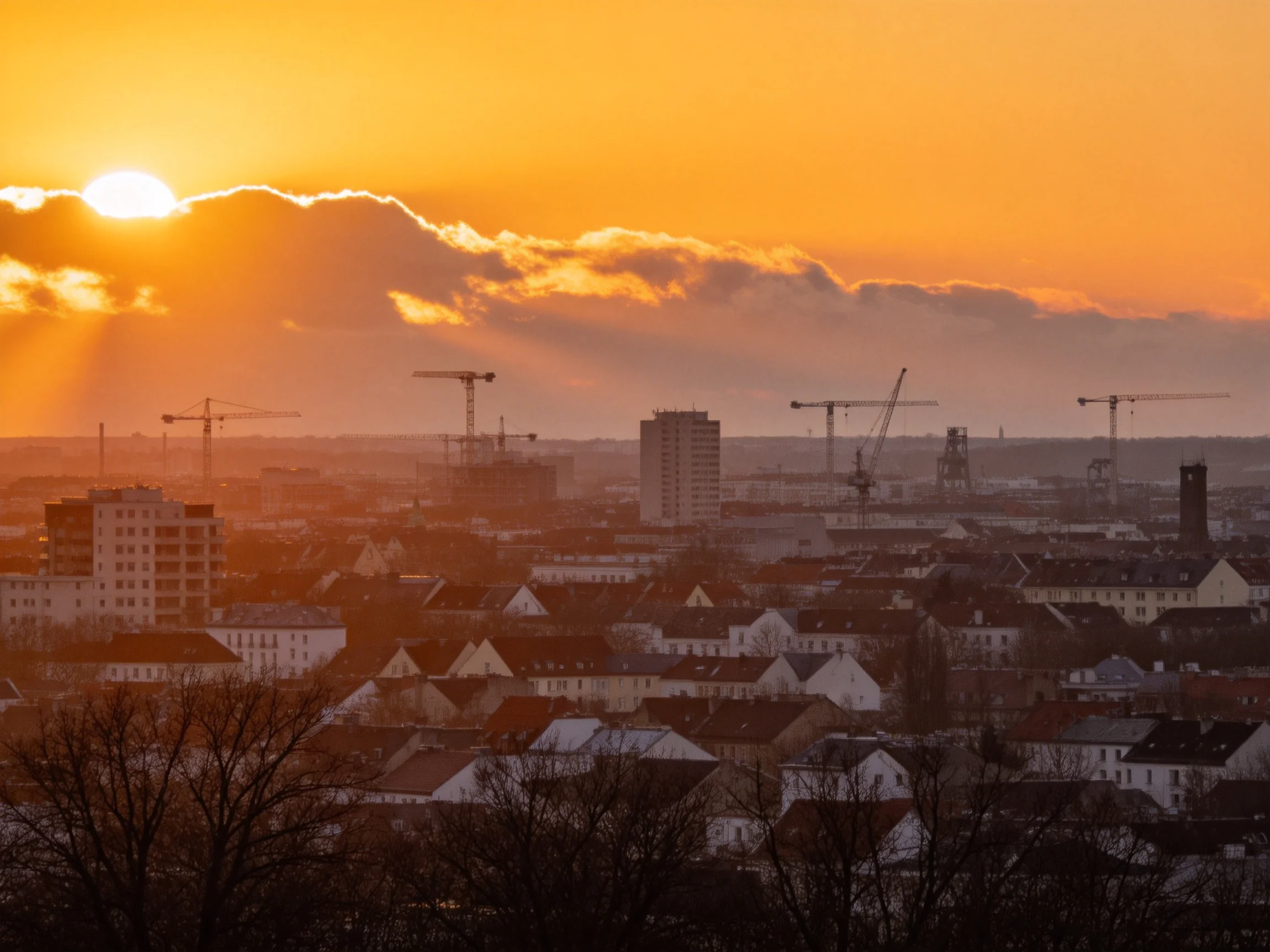 Sunset Illuminates Urban Landscape with Construction Cranes