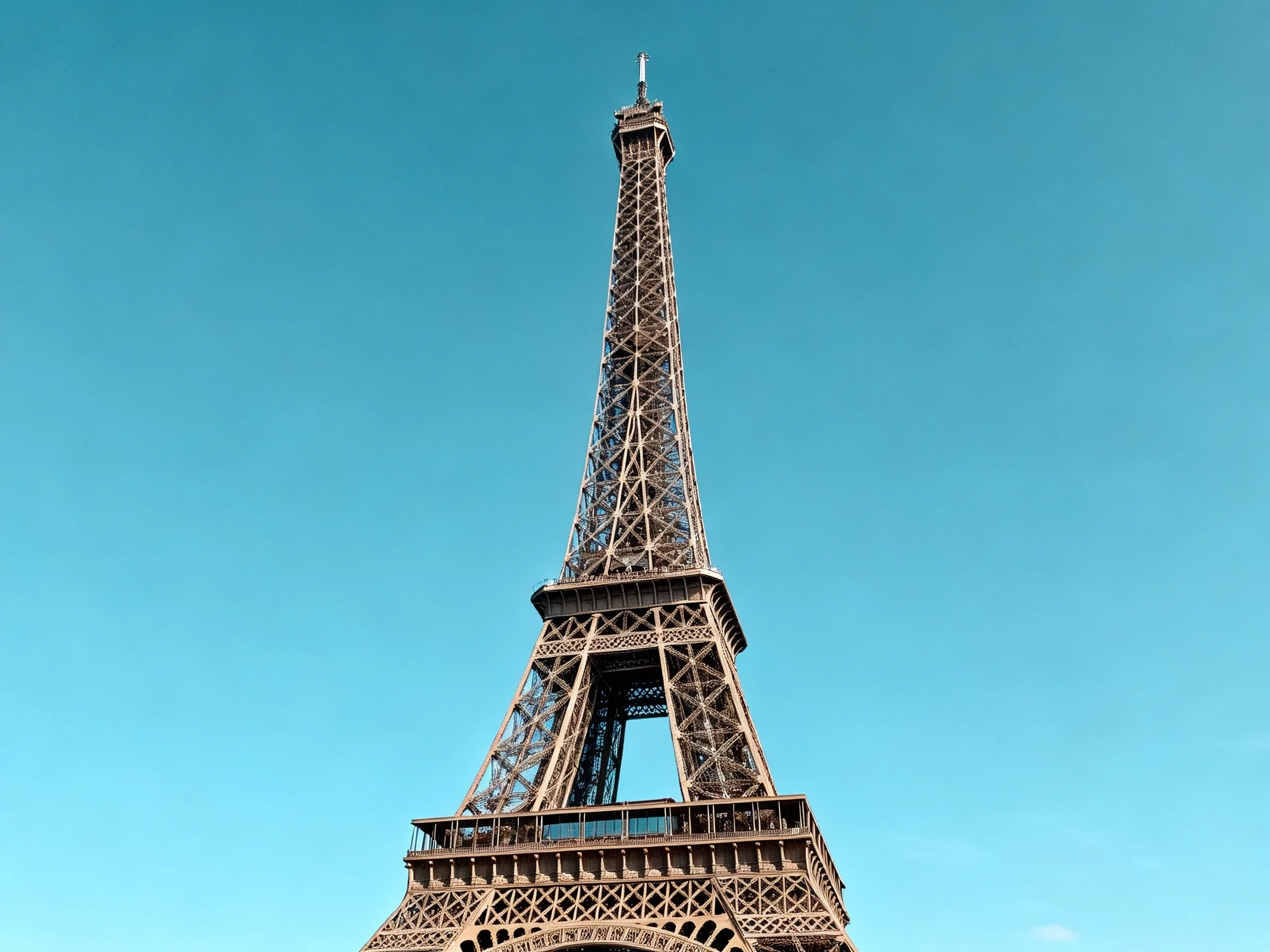 The Eiffel Towers iron lattice structure towers against a clear blue sky