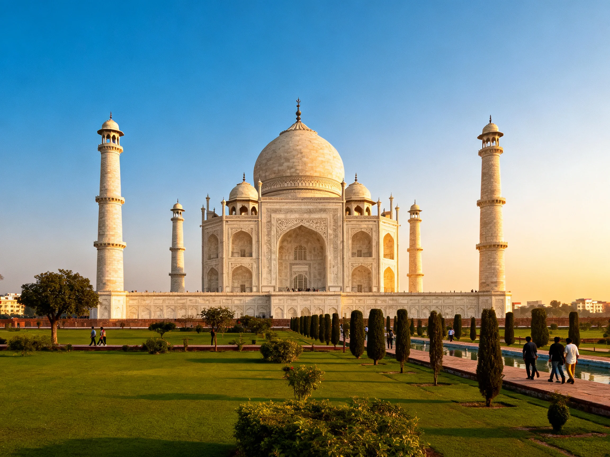 The Taj Mahal, a magnificent white marble monument, stands under a clear blue sky.