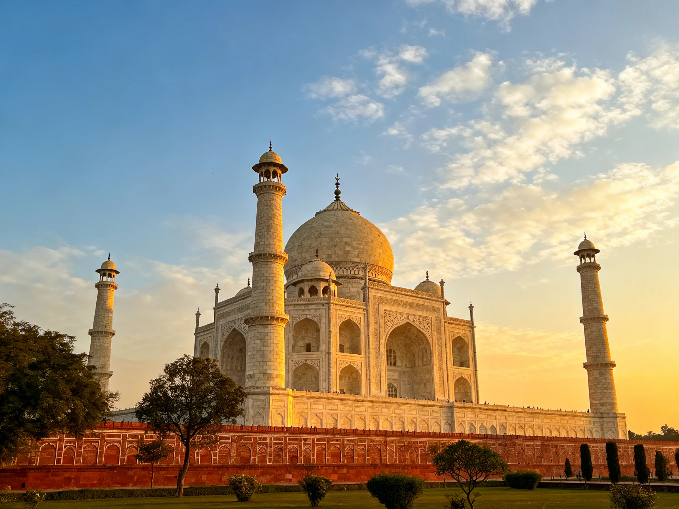 The Taj Mahal illuminated by golden sunset light with four minarets