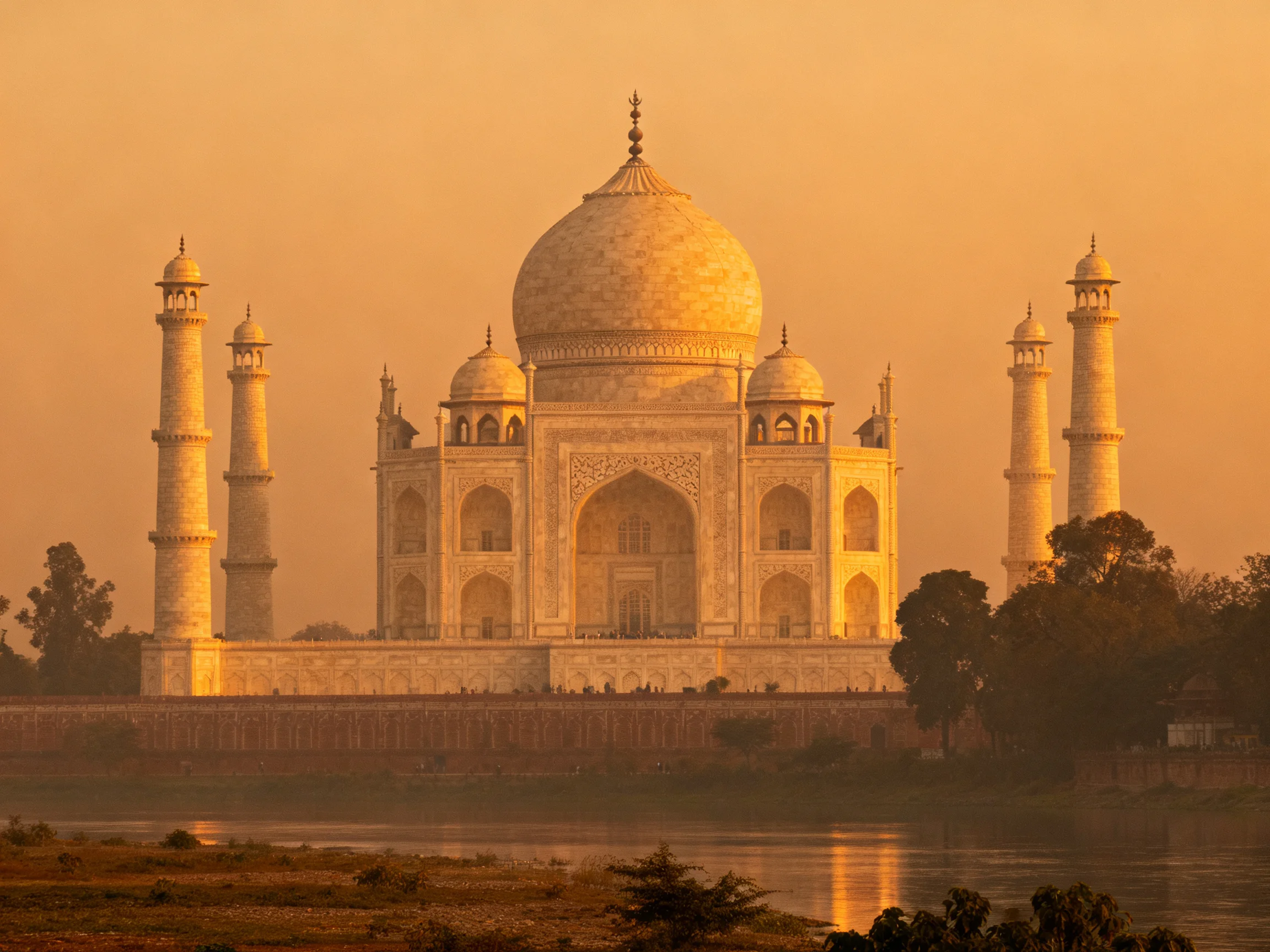 The Taj Mahal illuminated by golden sunset near tranquil waters
