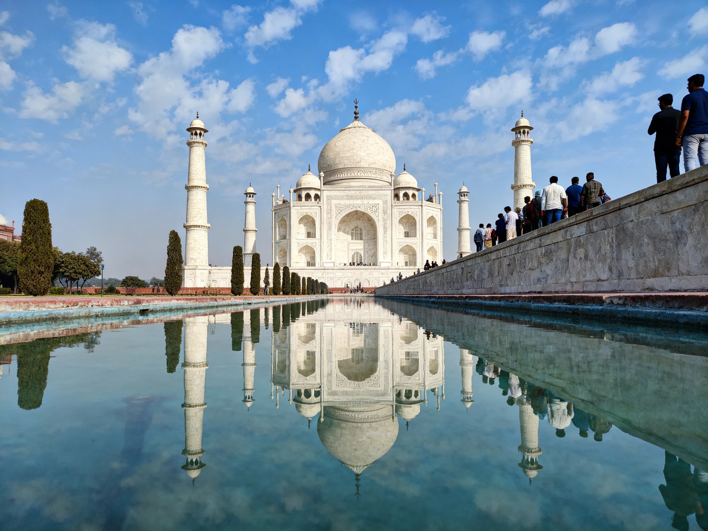 The Taj Mahal reflected in a long, clear pool under a bright sky