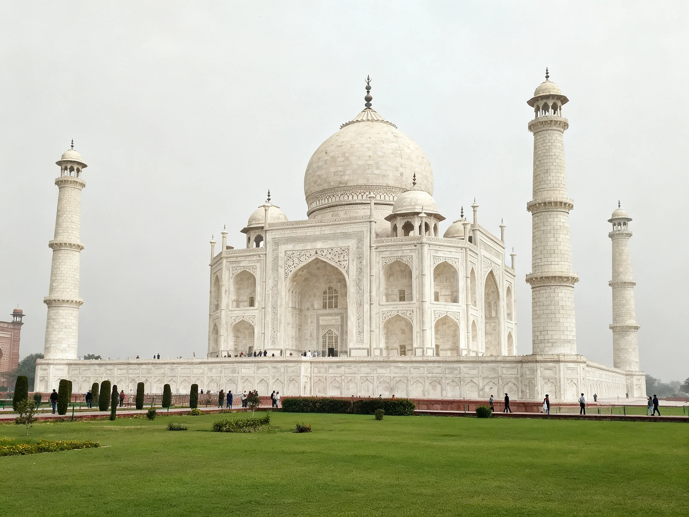 The magnificent white marble Taj Mahal with four minarets and sprawling green lawn