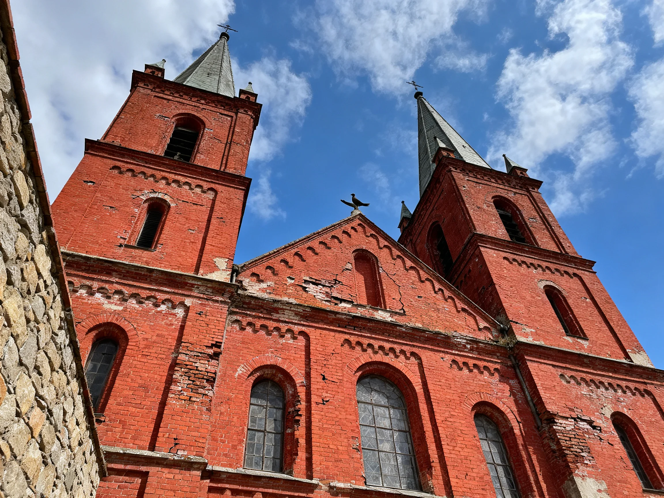 Two tall red-brick church towers against a bright blue sky