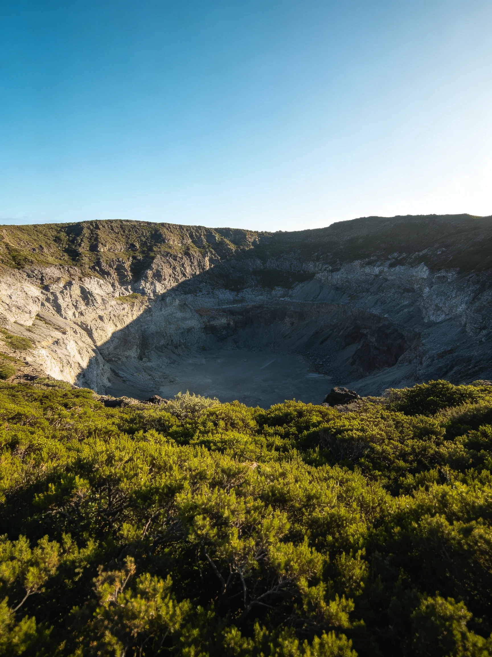 A large volcanic crater with rugged rocky walls and lush green vegetation