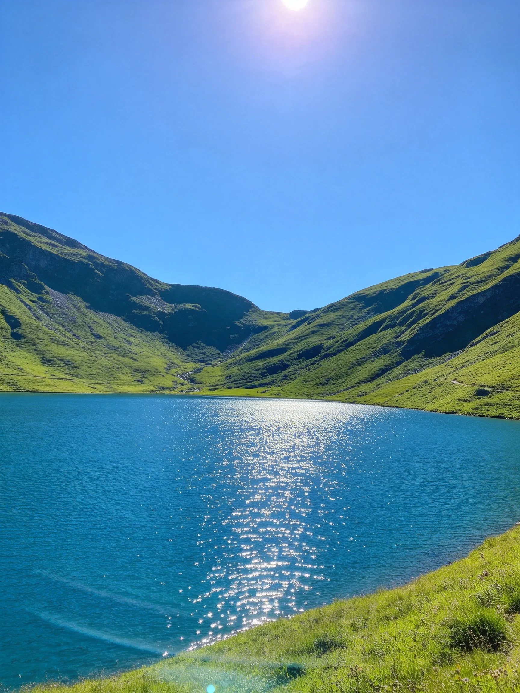 A serene blue lake surrounded by green mountain slopes under sunny skies