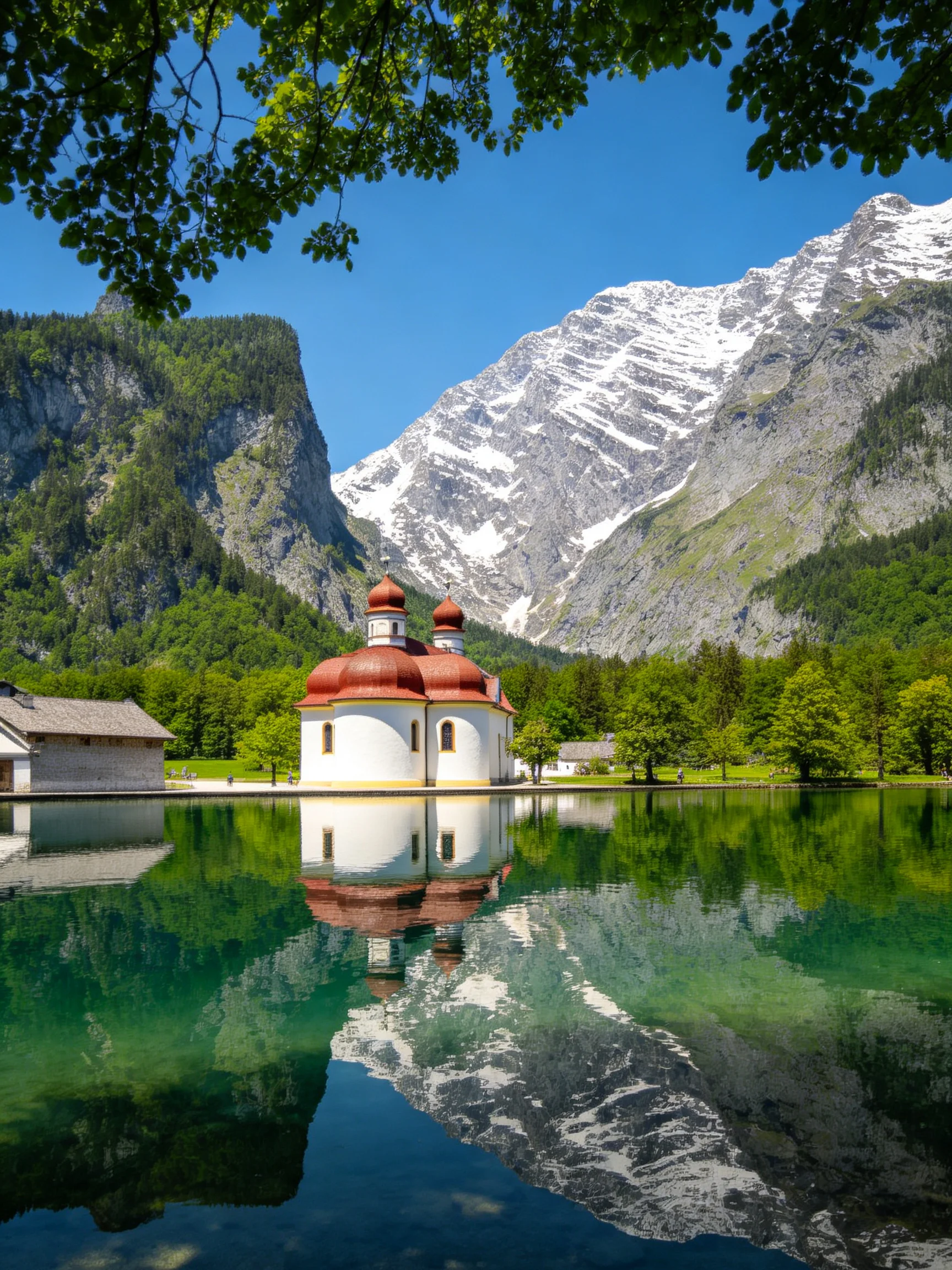 A white church with red domes sits by a turquoise lake near snow-capped mountains