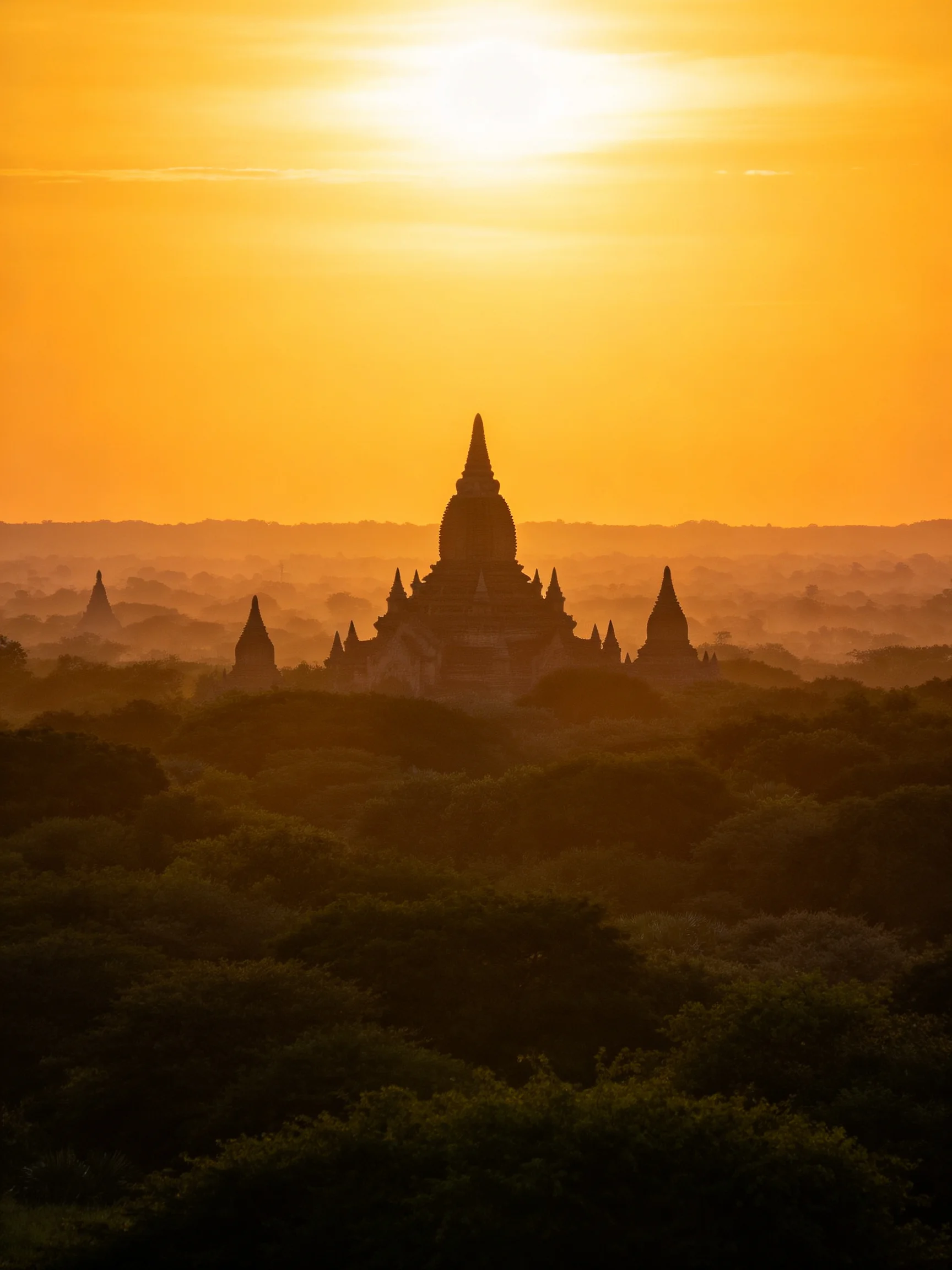 Golden Sunset Illuminates Ancient Temple Silhouettes Among Dense Forest
