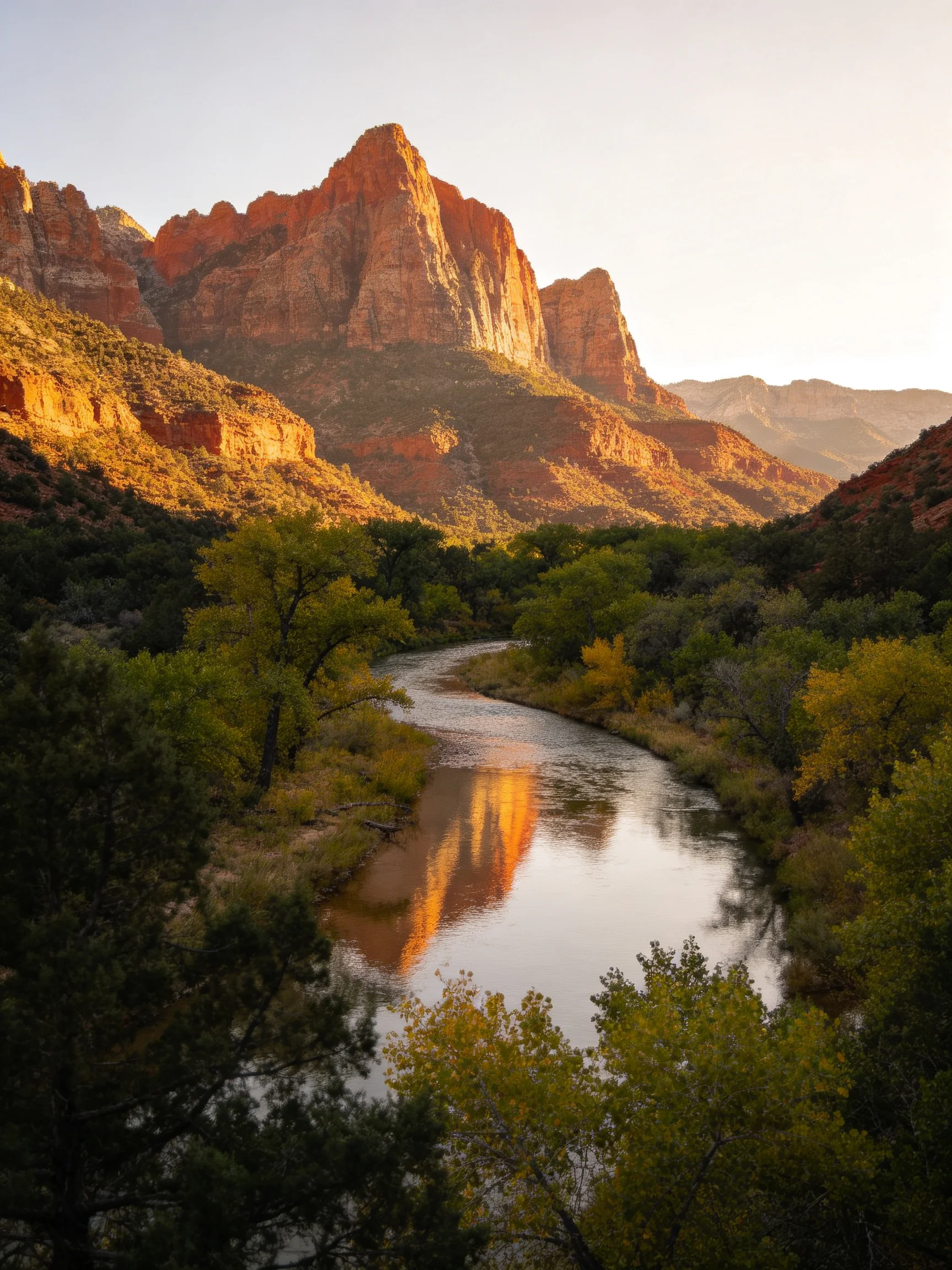 Golden light illuminates red rock cliffs reflecting in a winding river with lush greenery
