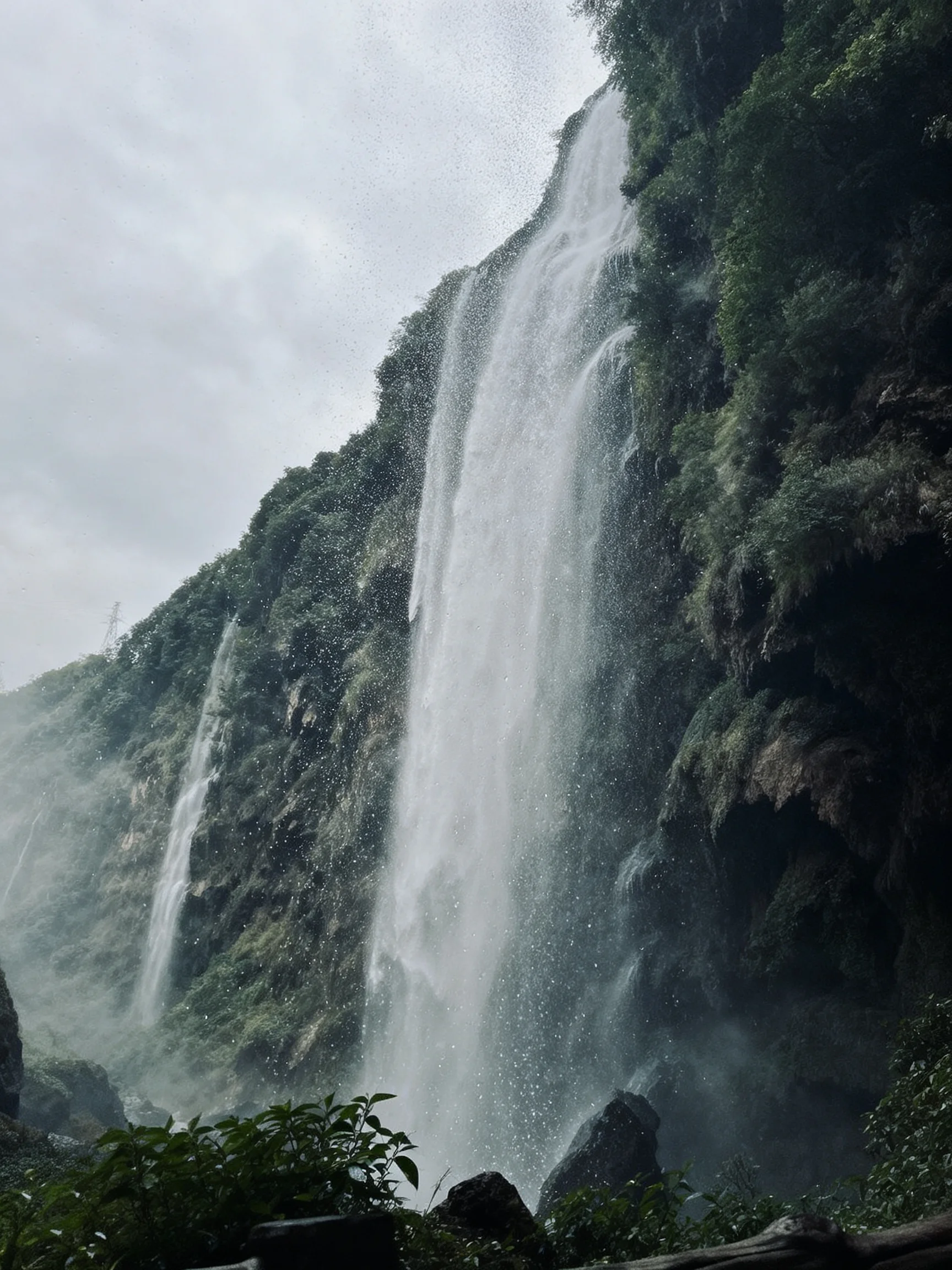 Towering Waterfalls Over Lush Green Cliffs with Misty Spray