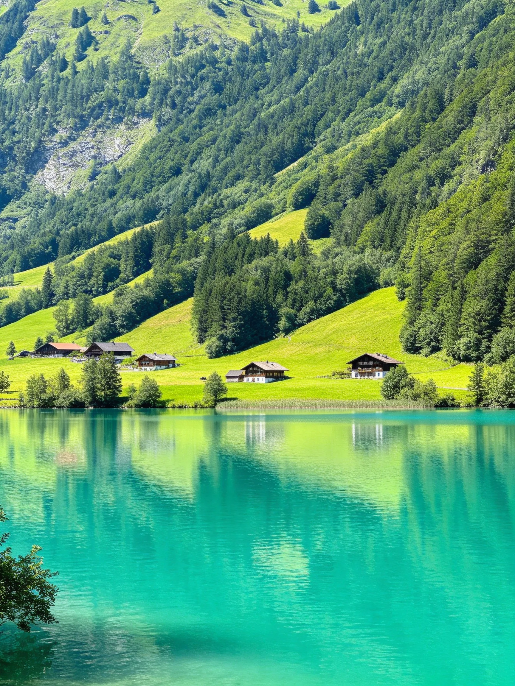 Turquoise Lake Reflects Green Hills and Wooden Cabins