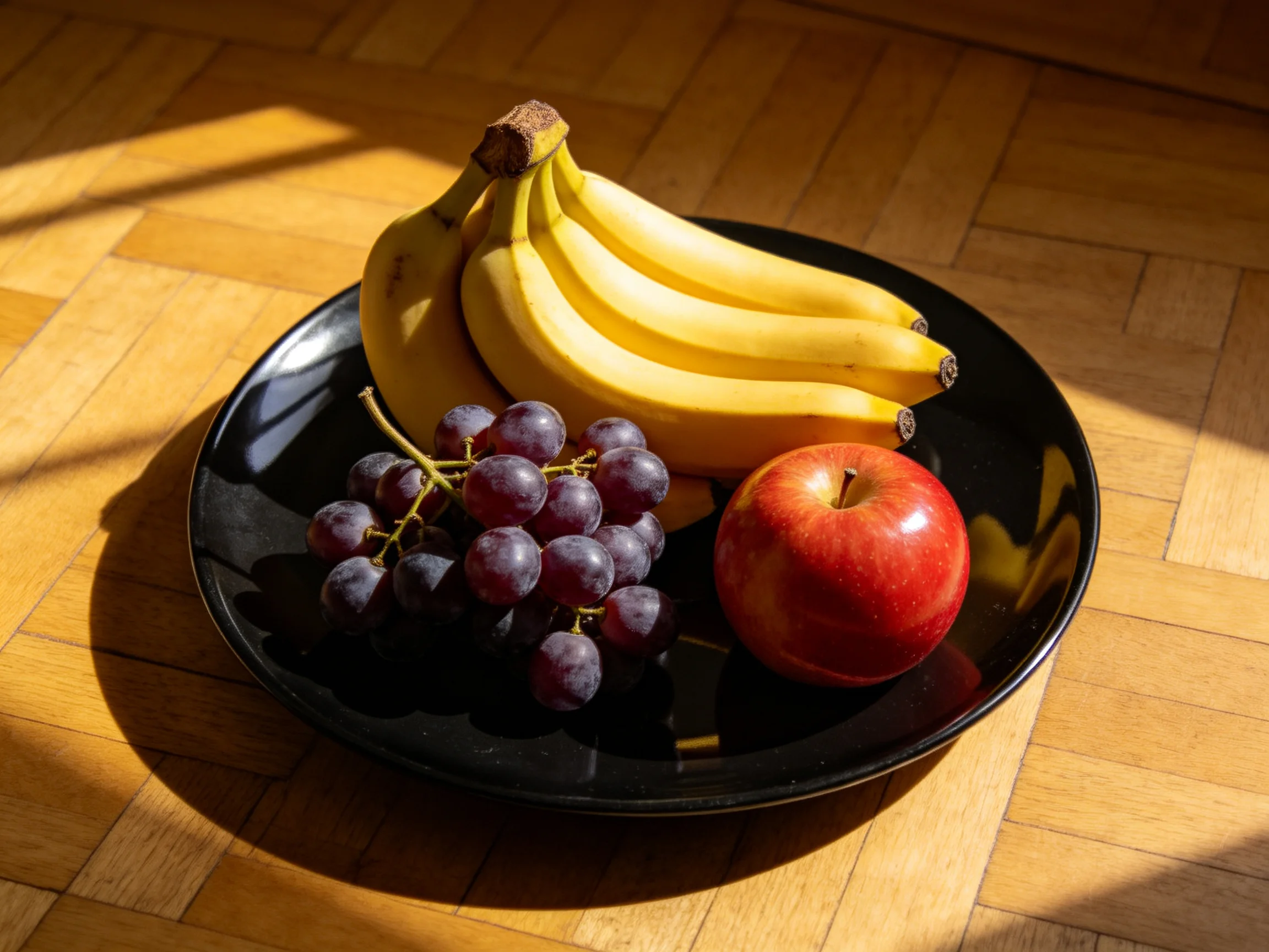 A black plate holds bananas, grapes, and a red apple with vibrant colors