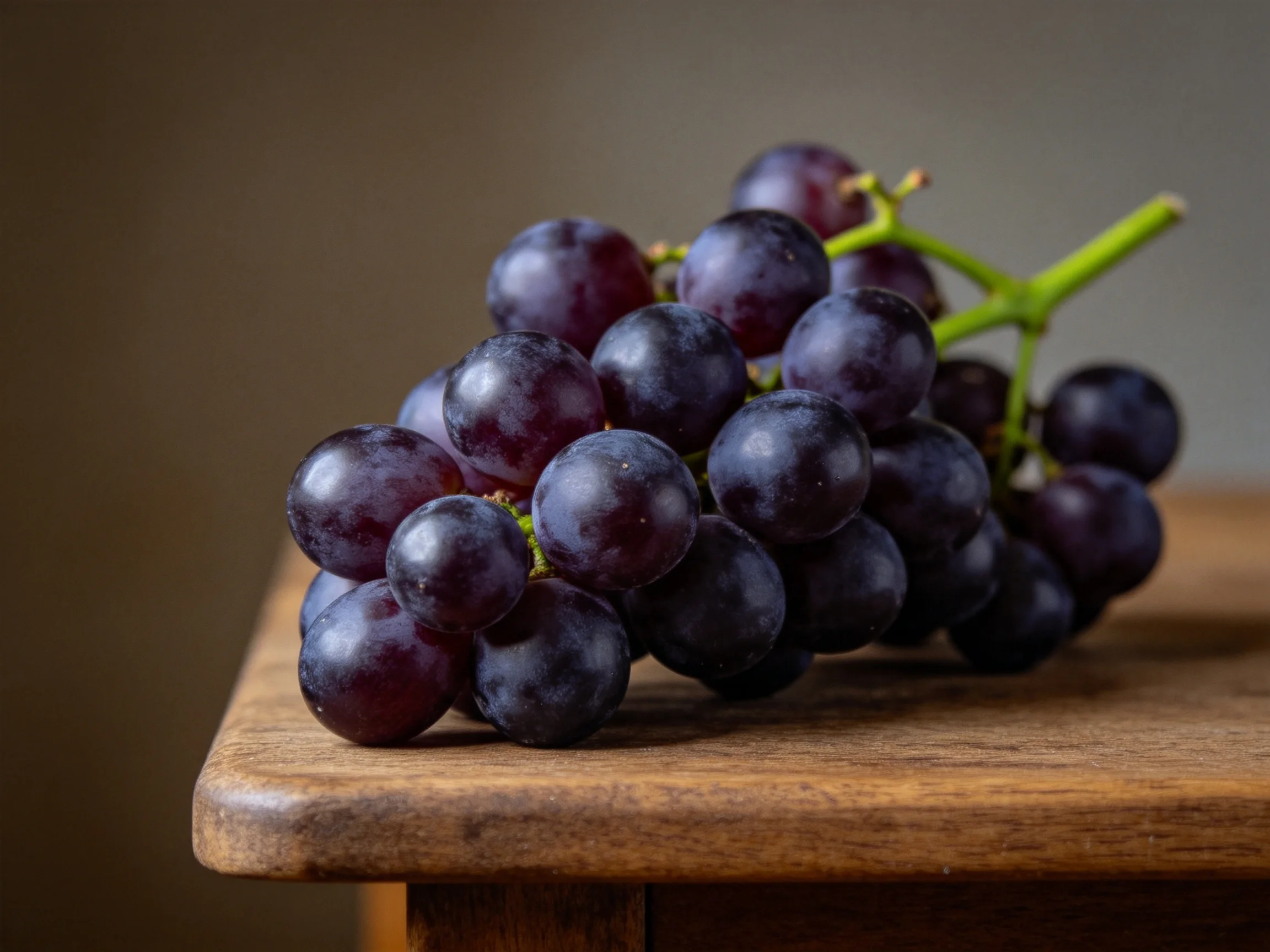 A cluster of deep purple grapes rests on a wooden table