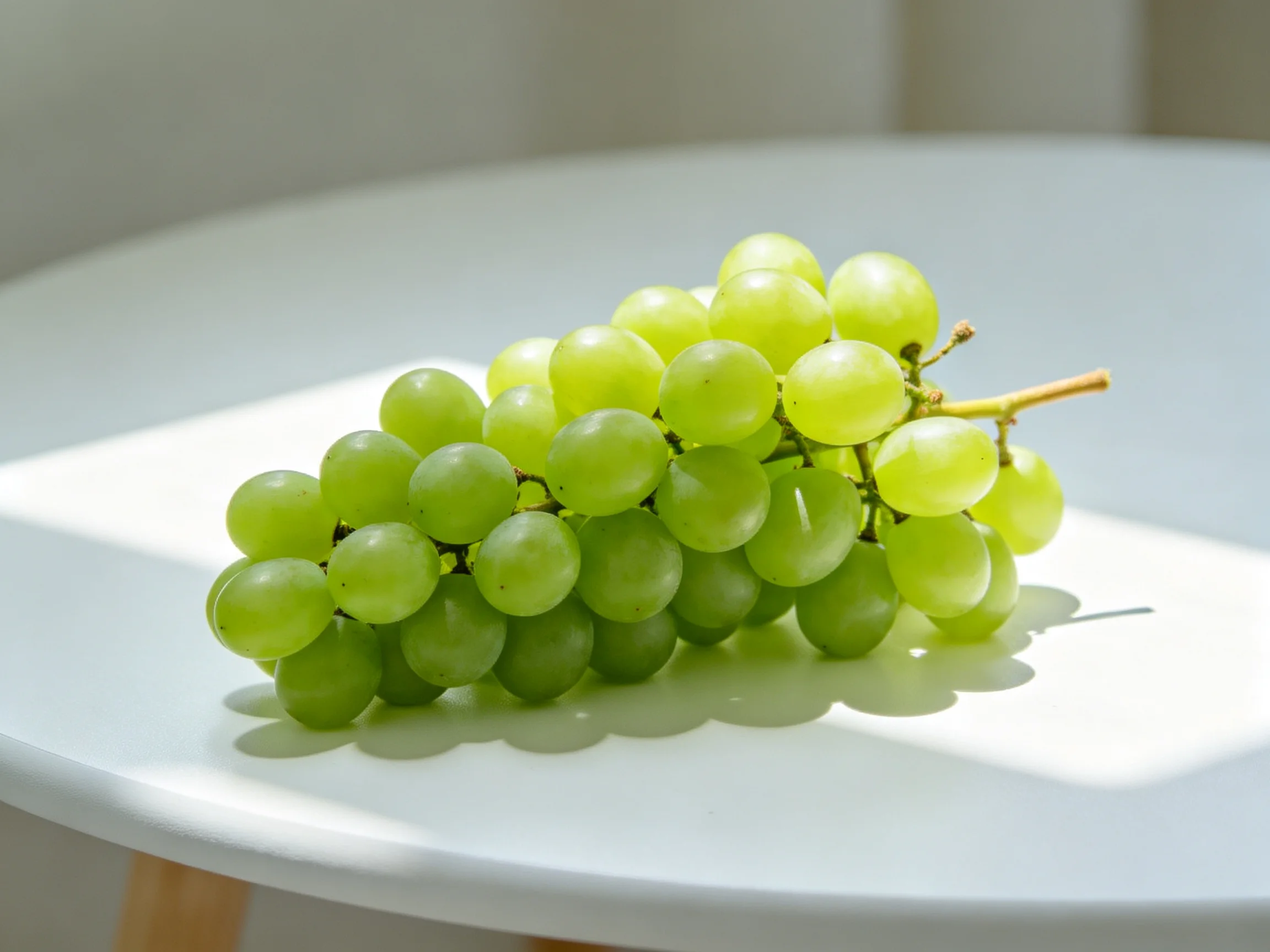 A cluster of fresh green grapes on a white round table