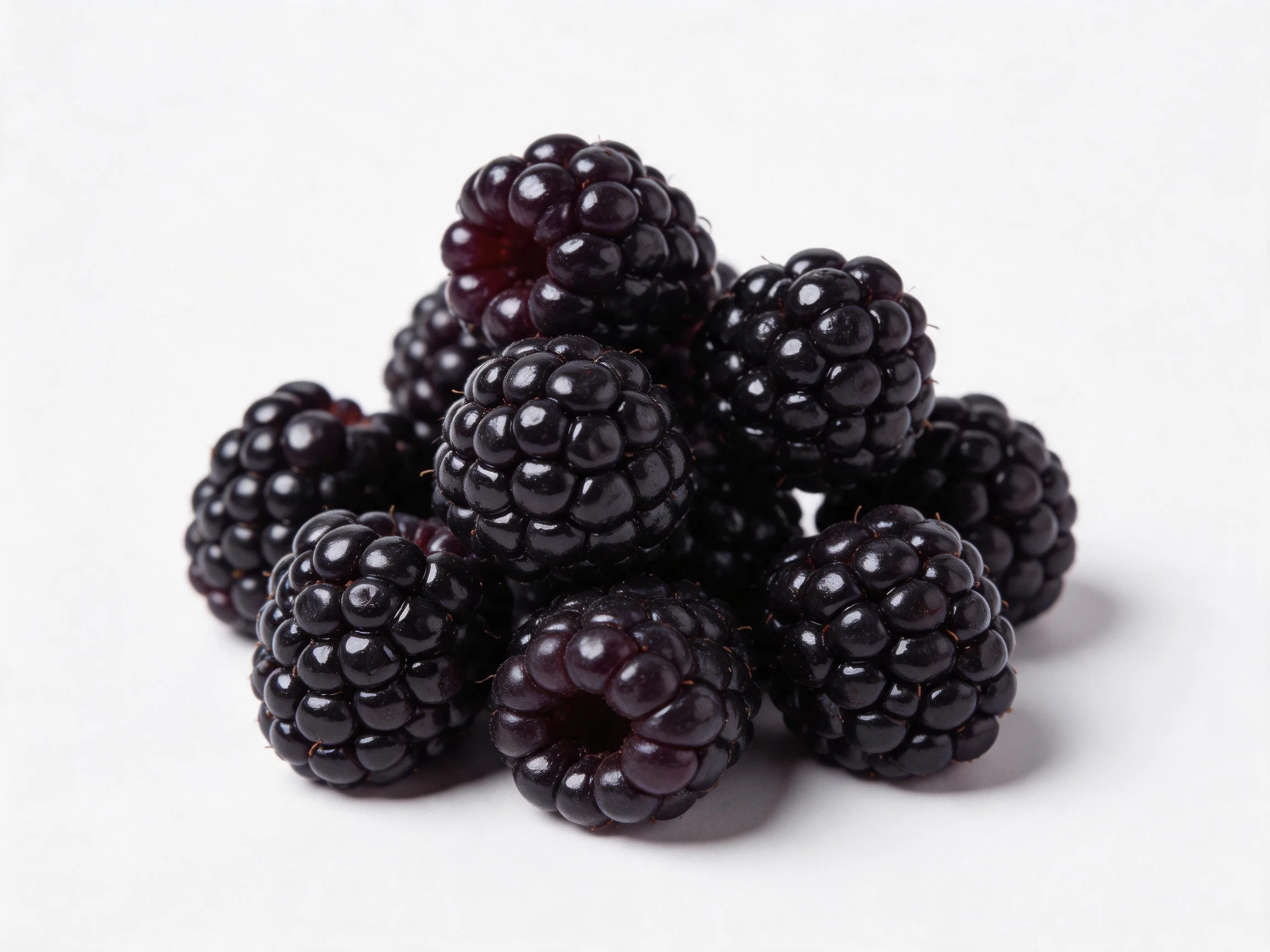 A cluster of glossy, deep-purple blackberries arranged in a mound
