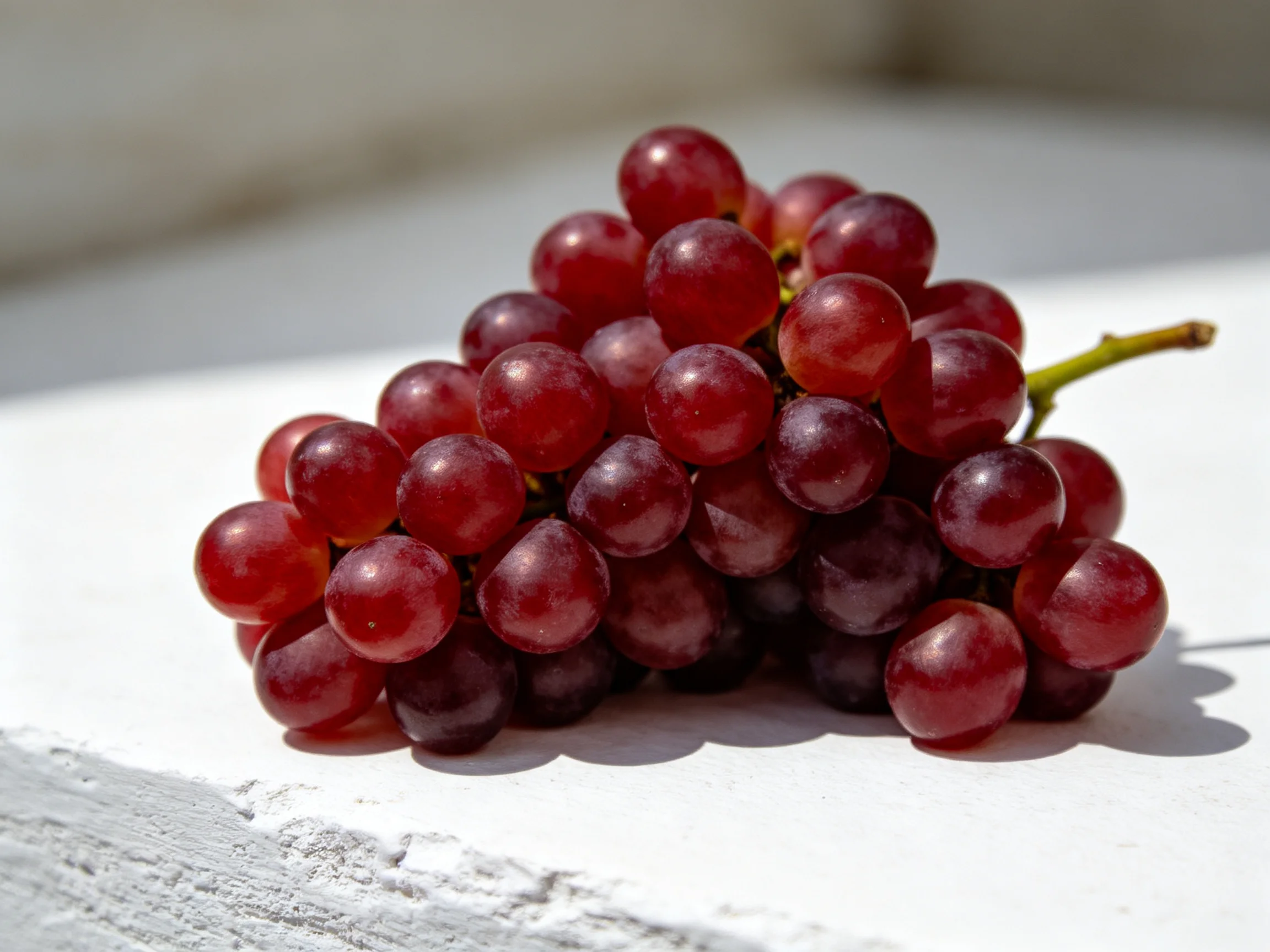 A cluster of plump red grapes rests on a bright white surface