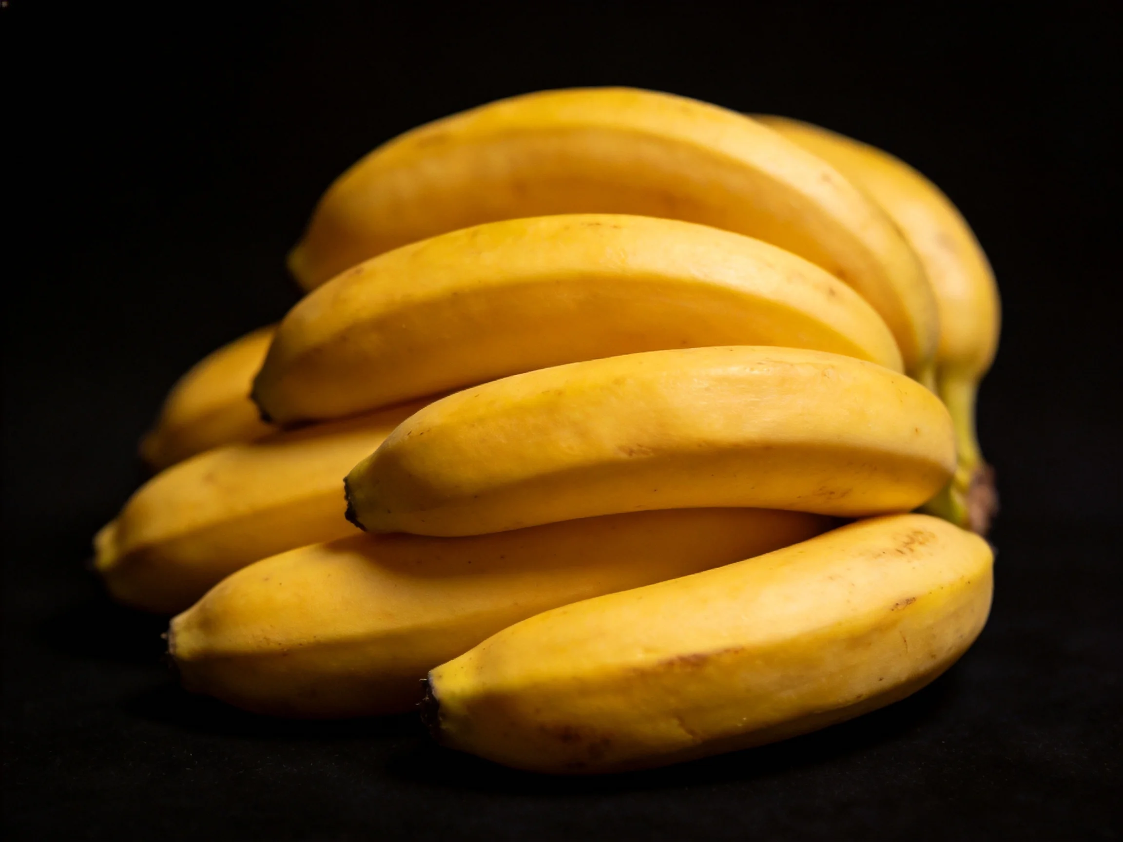 A cluster of ripe yellow bananas against a dark backdrop