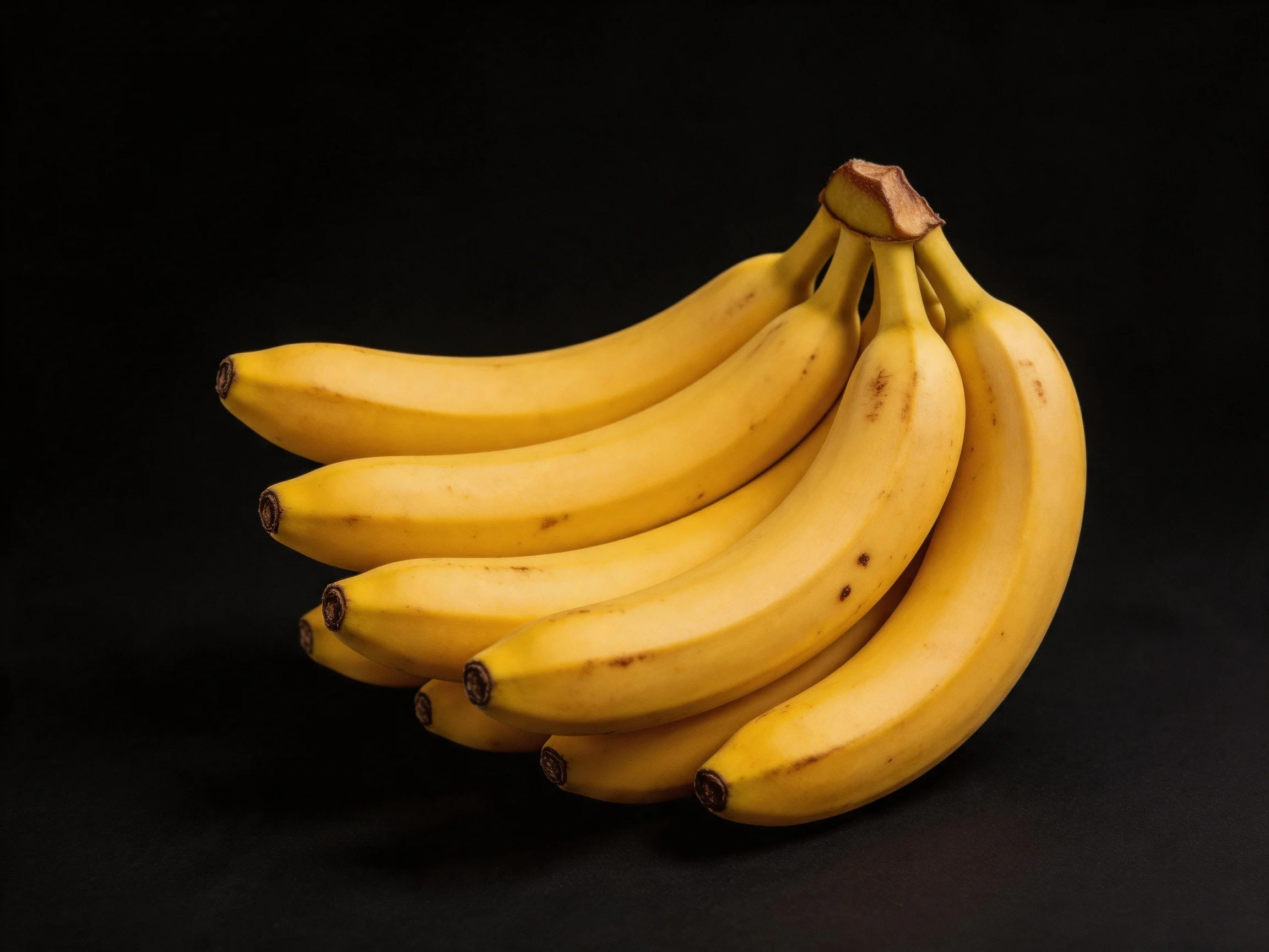 A cluster of ripe yellow bananas against a solid black background