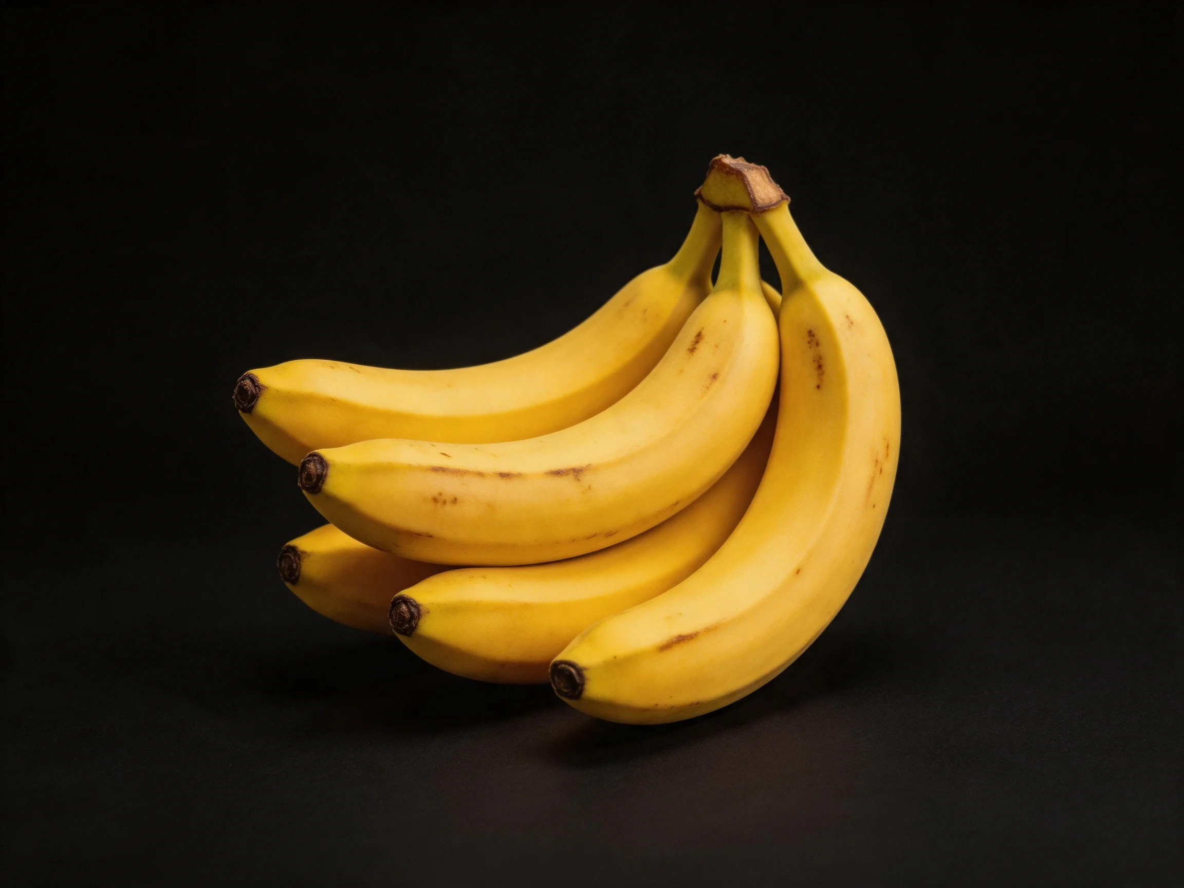 A cluster of ripe yellow bananas on a black background