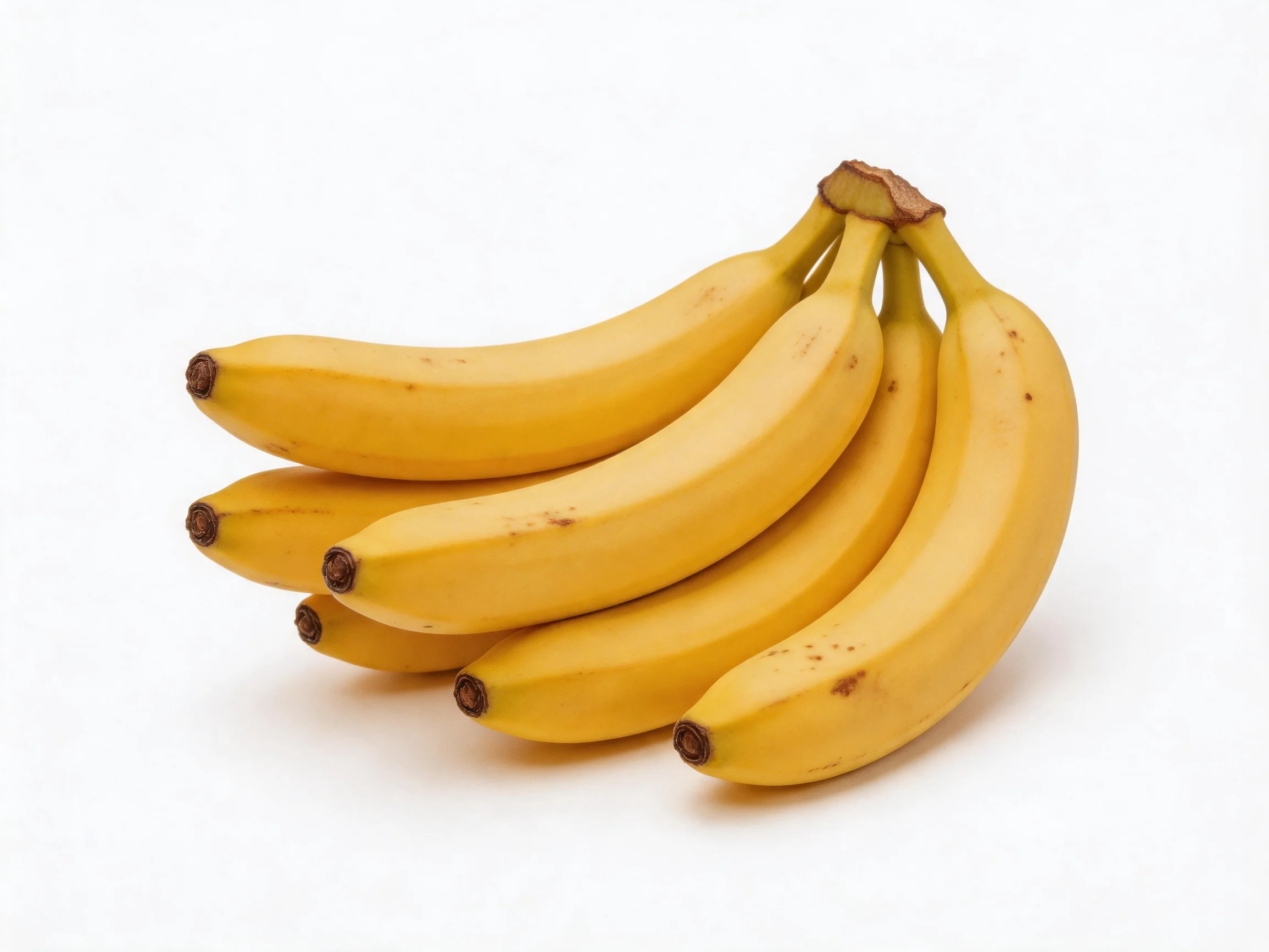 A cluster of six bright yellow bananas on a white surface