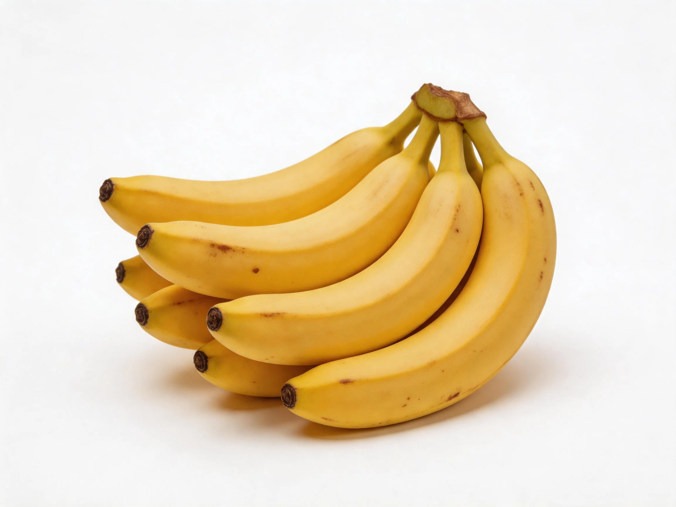 A cluster of six ripe yellow bananas on a plain white surface