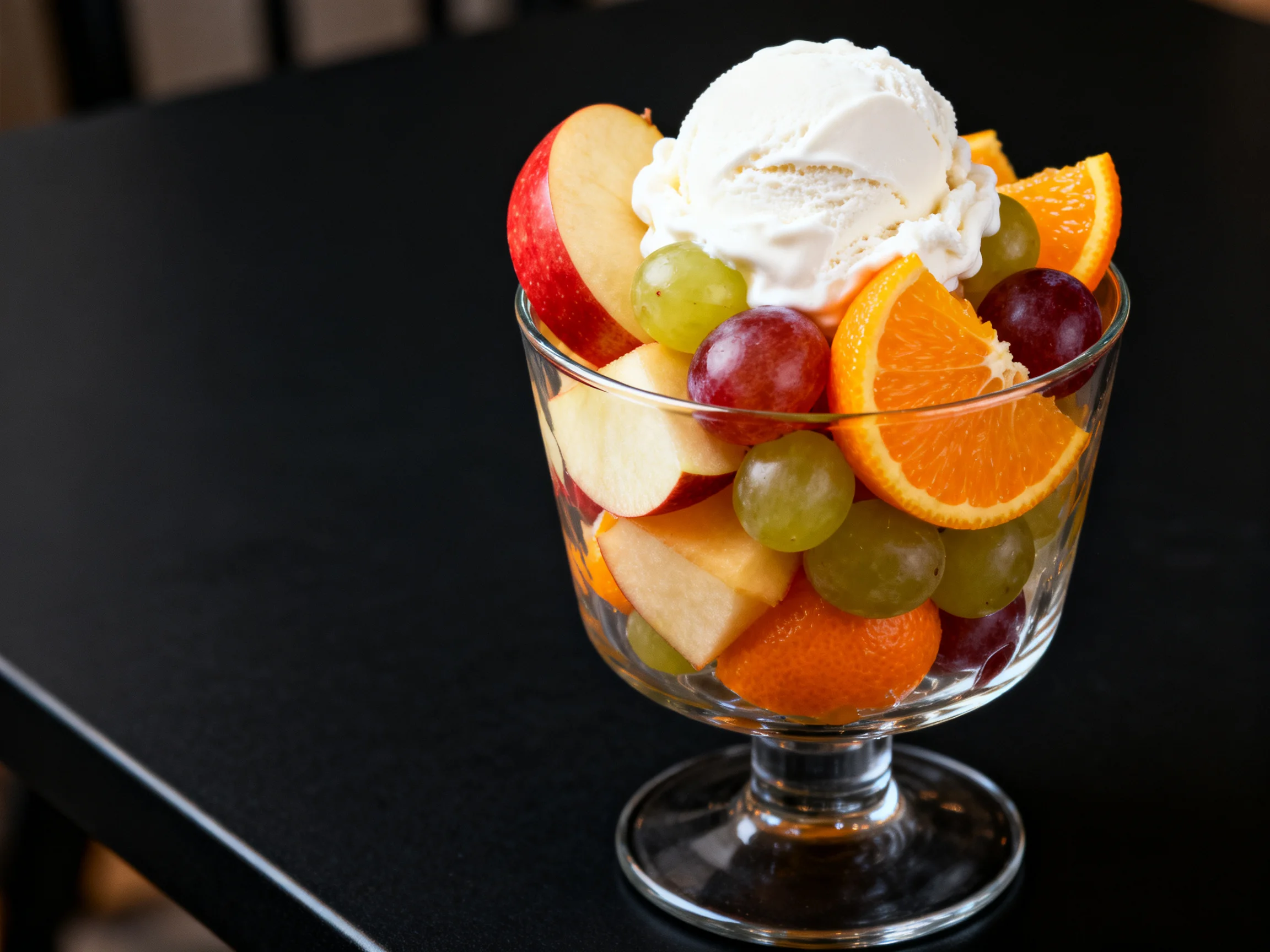 A glass bowl of mixed fruits topped with vanilla ice cream