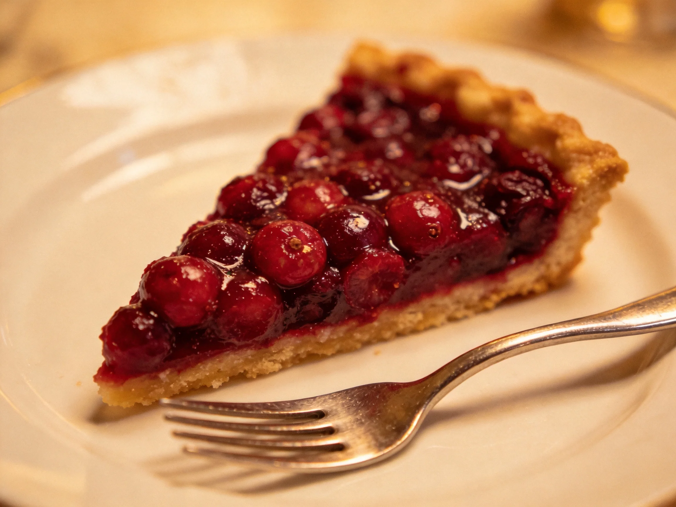 A golden-brown crust encases a glossy red berry-filled tart slice