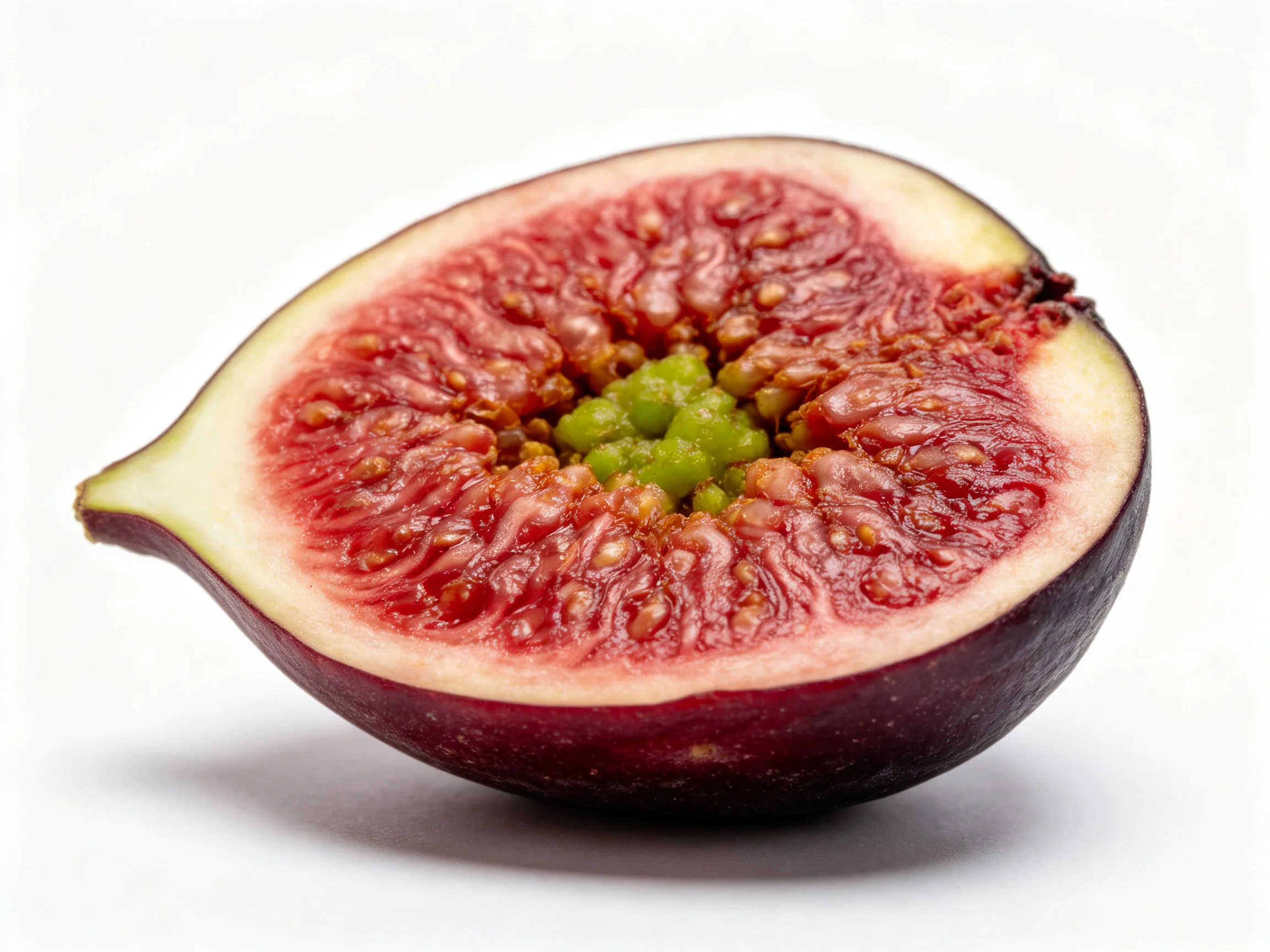 A halved fig reveals deep red flesh and green center