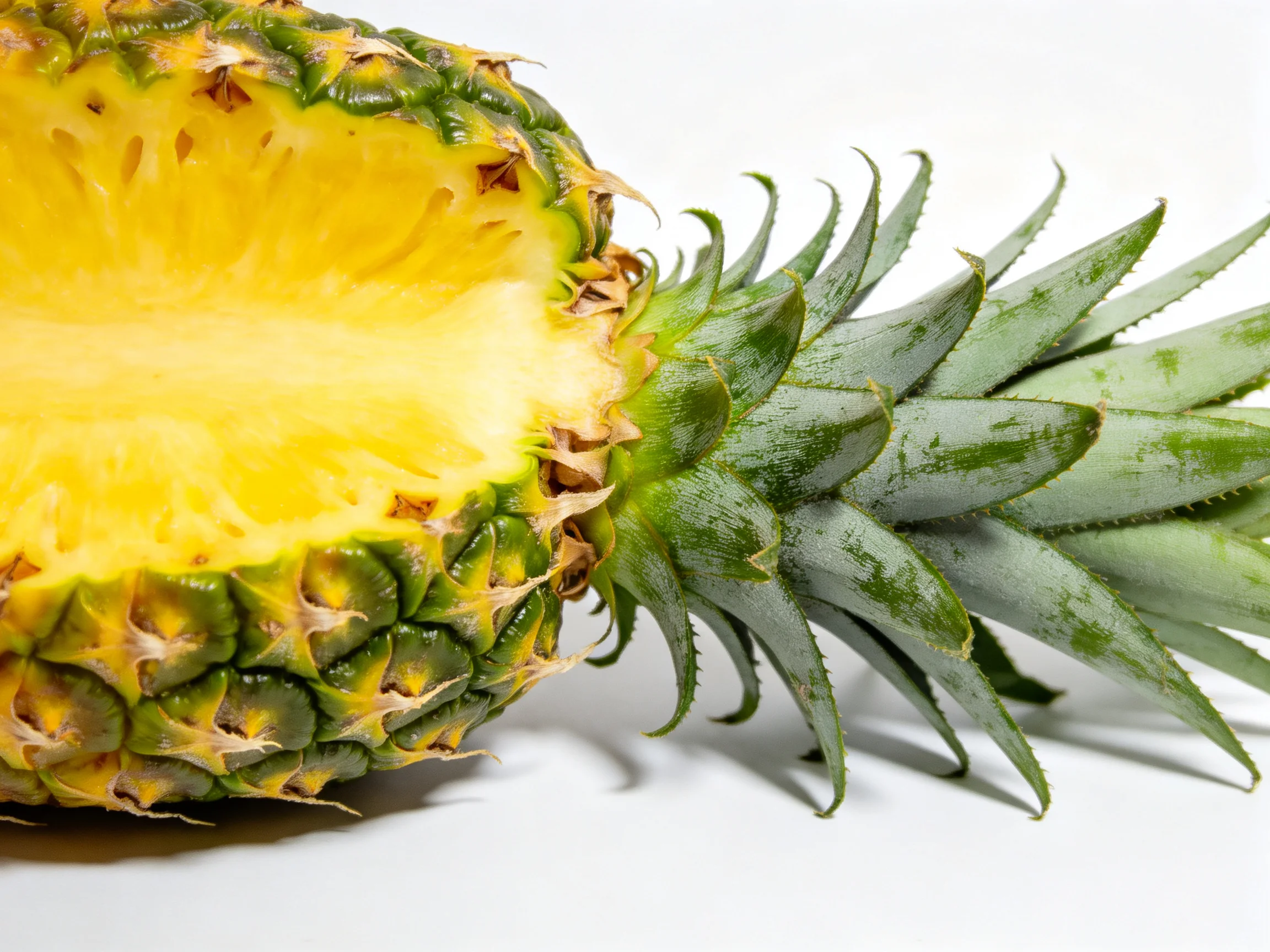 A halved pineapple with vibrant yellow flesh and textured green exterior