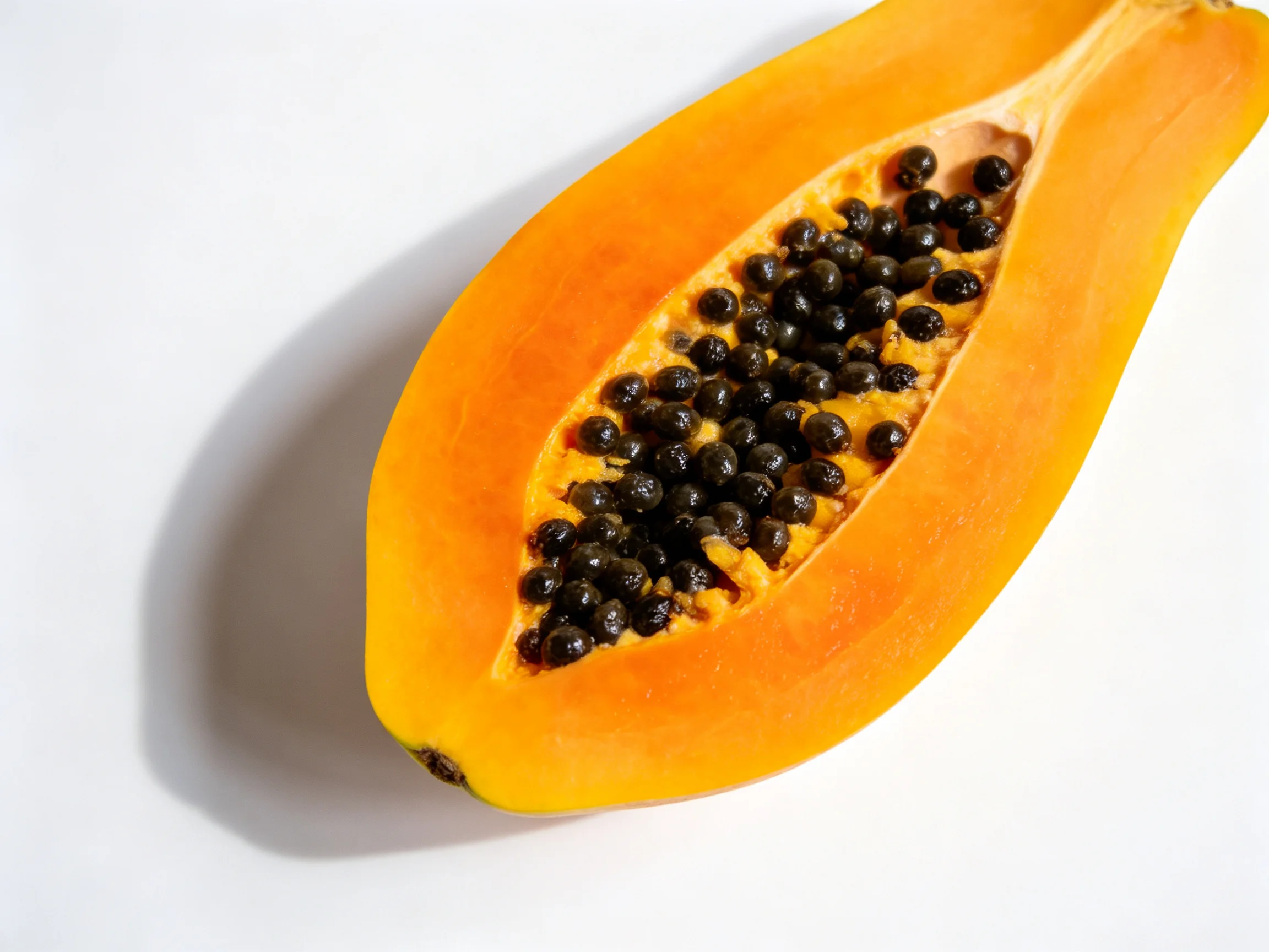 A halved ripe papaya with vibrant orange flesh and dark seeds
