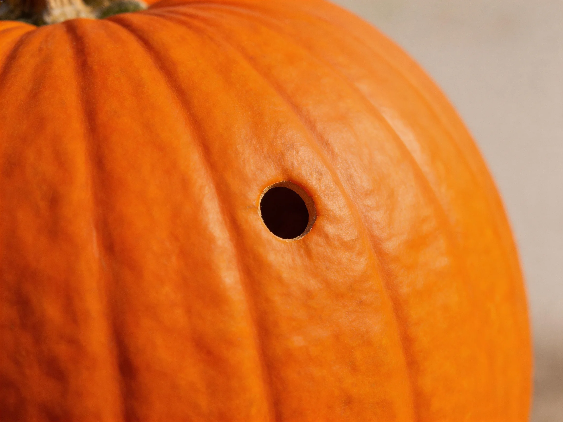 A large orange pumpkin with a single dark circular hole