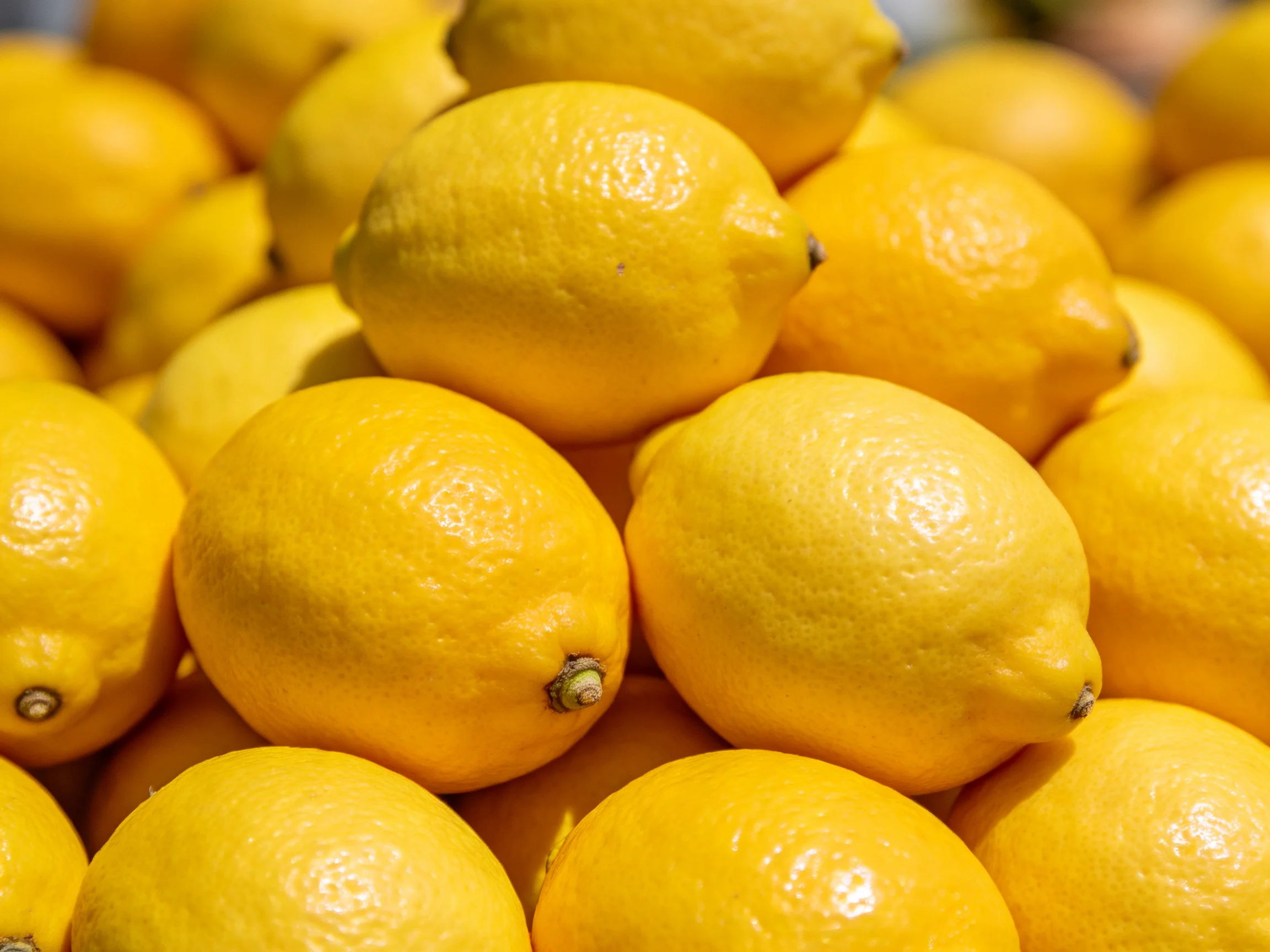 A large pile of bright yellow lemons stacked closely together