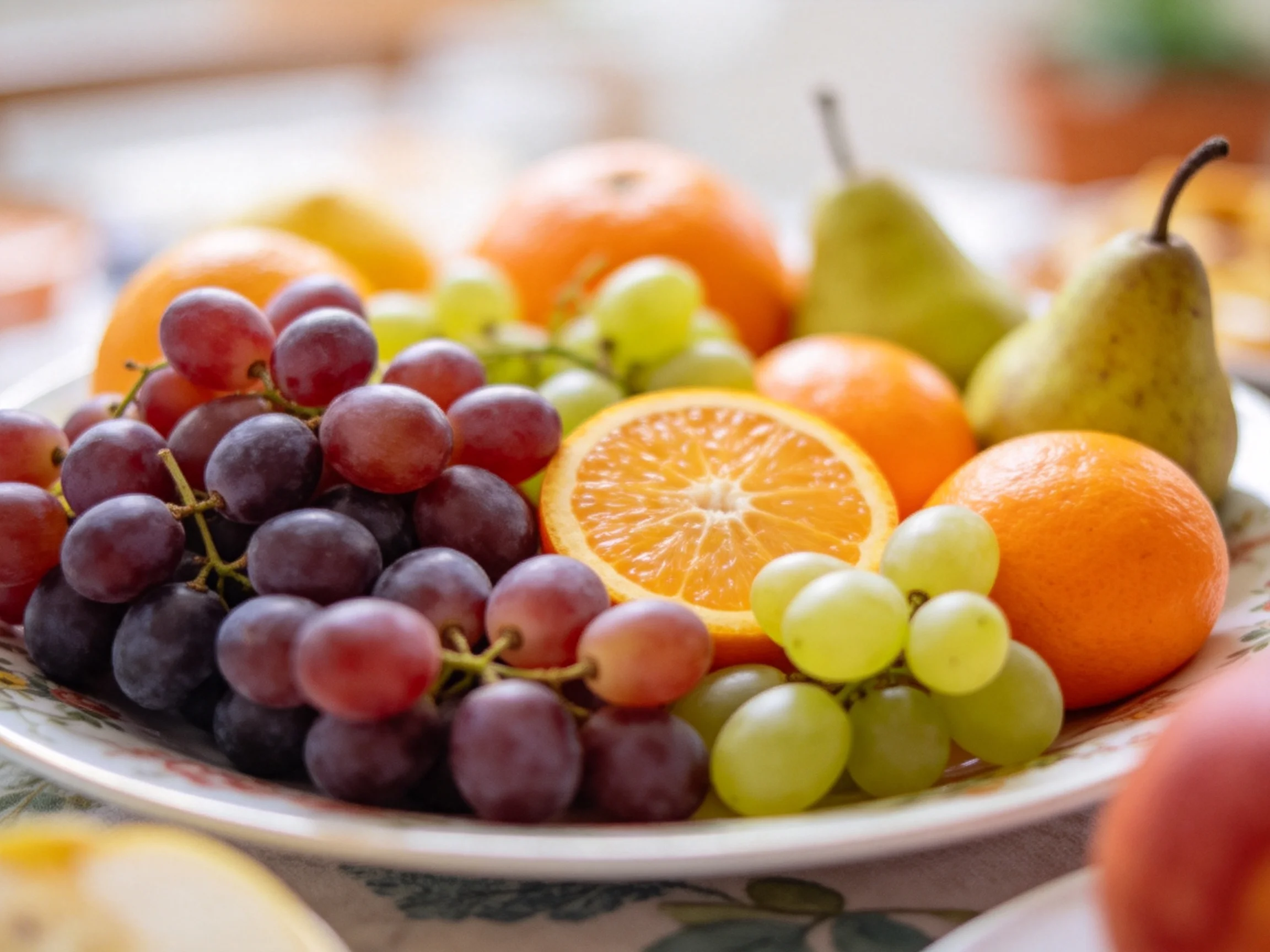 A plate filled with assorted fresh fruits such as grapes, oranges, and pears