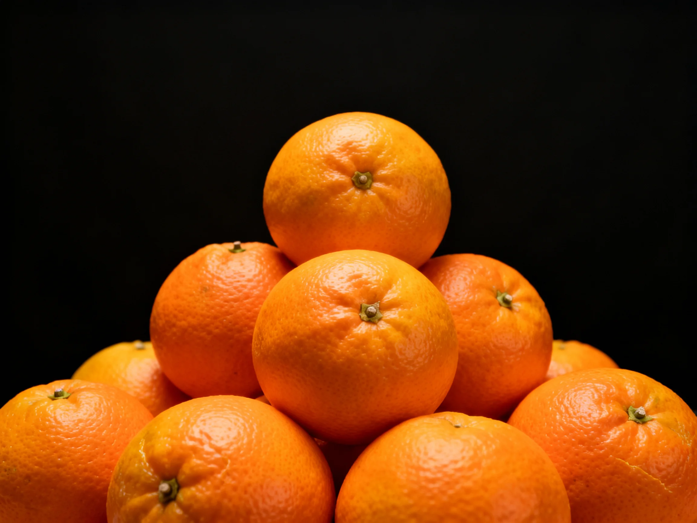 A pyramid of vibrant oranges arranged in a triangular formation
