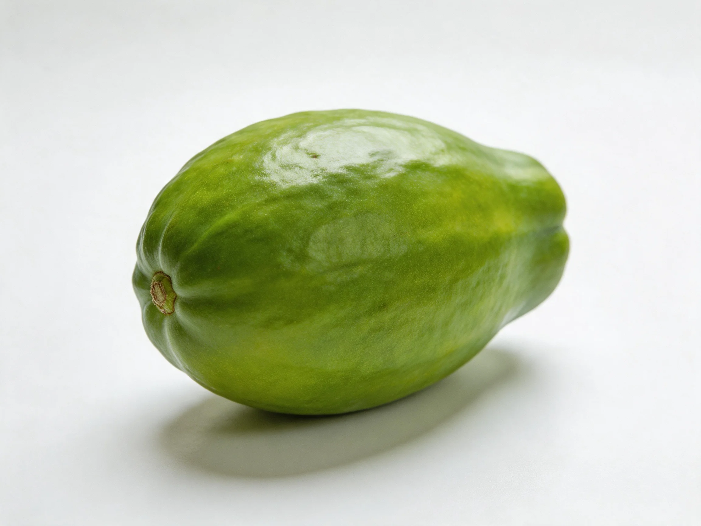 A single green papaya with glossy skin on a white background