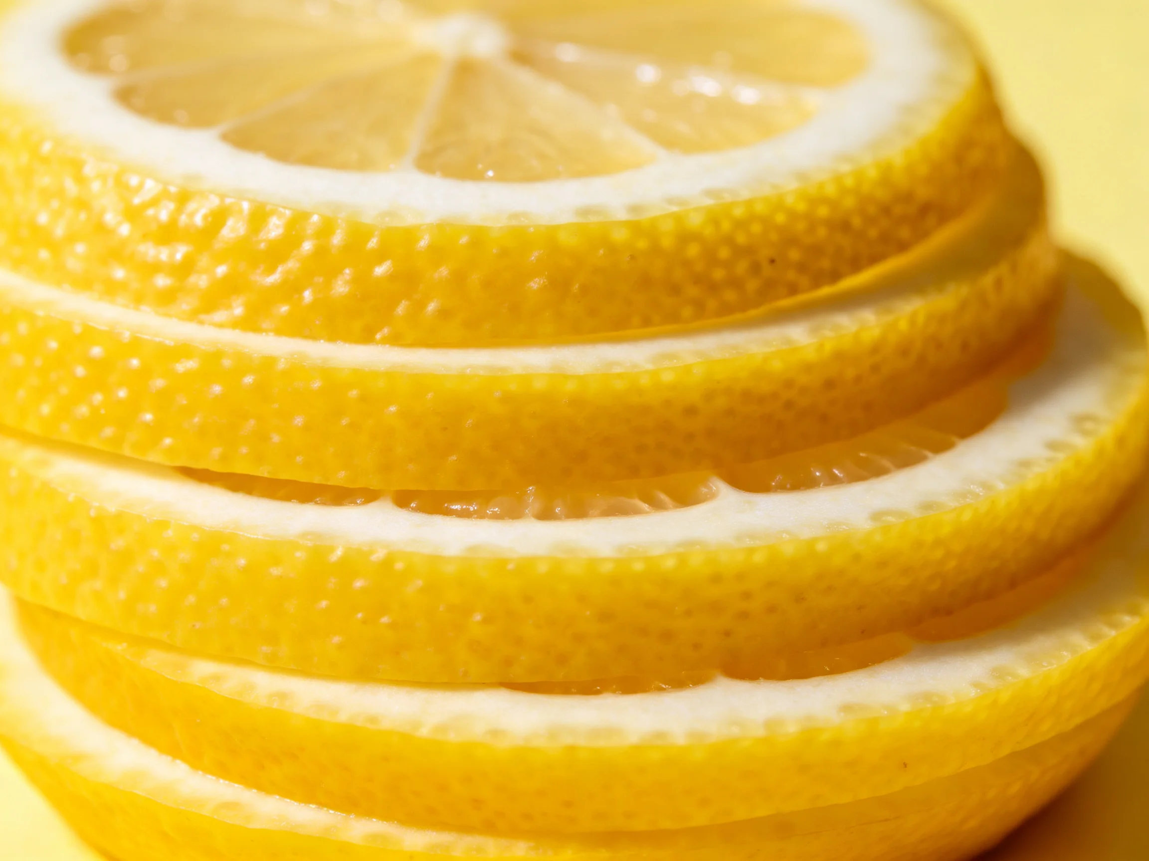 A stack of five bright yellow lemon slices with white interiors