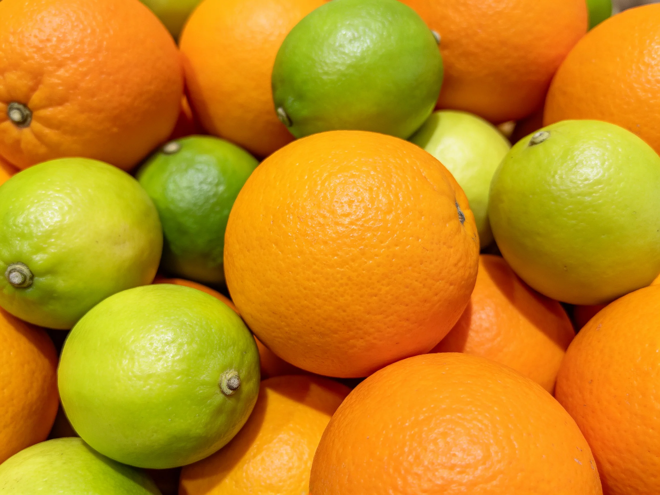A vibrant assortment of oranges and green limes displayed closely together