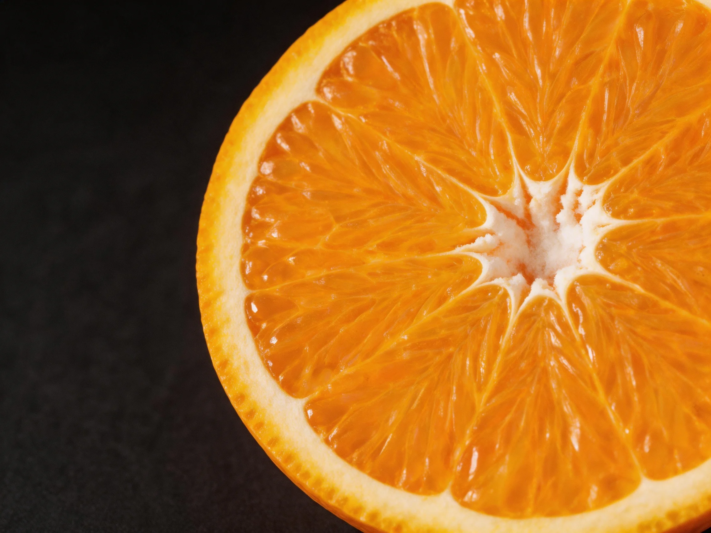 A vibrant orange citrus fruit sliced open, showcasing juicy segments