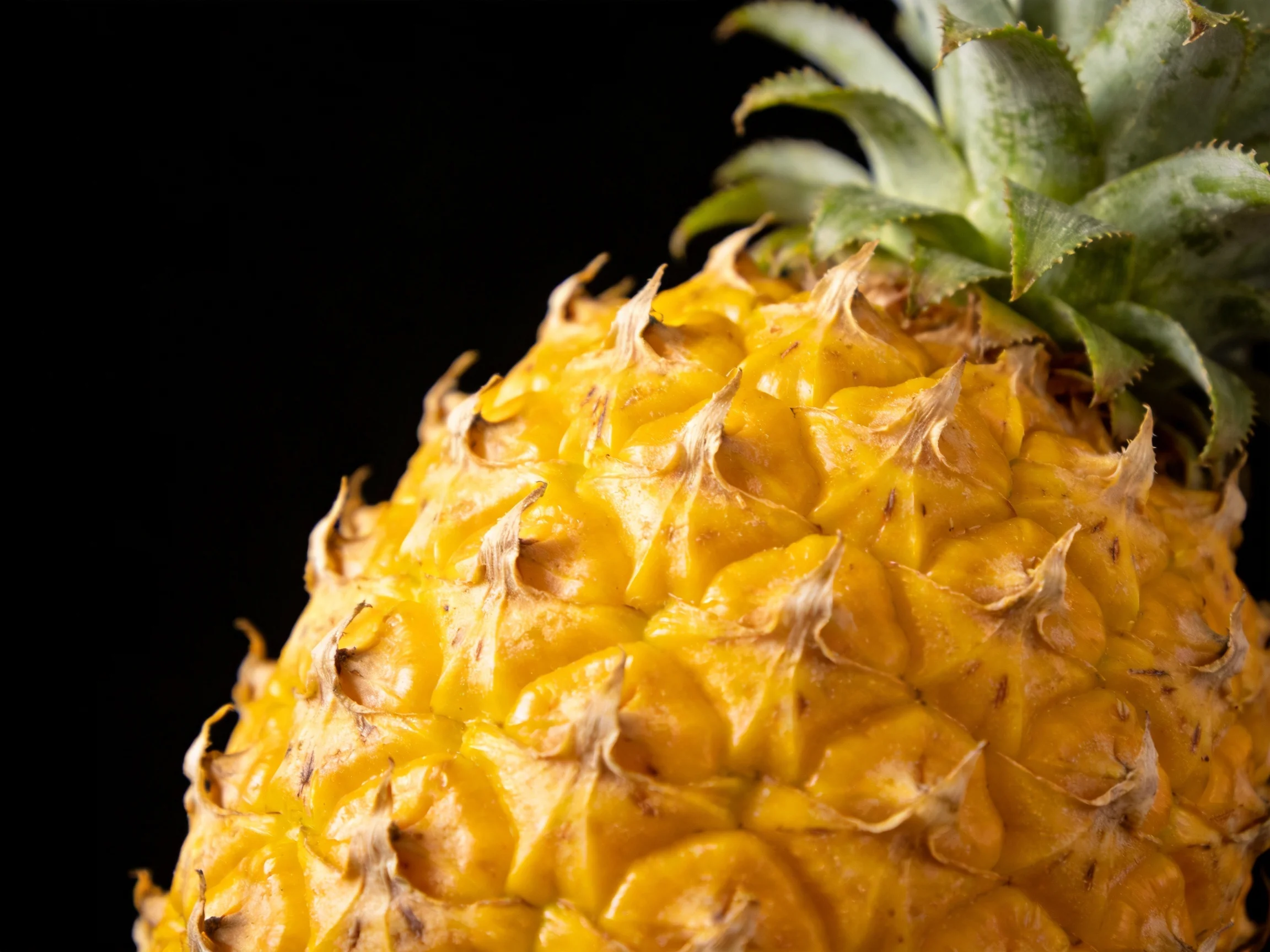 A vibrant yellow pineapple with textured rind and green leafy crown