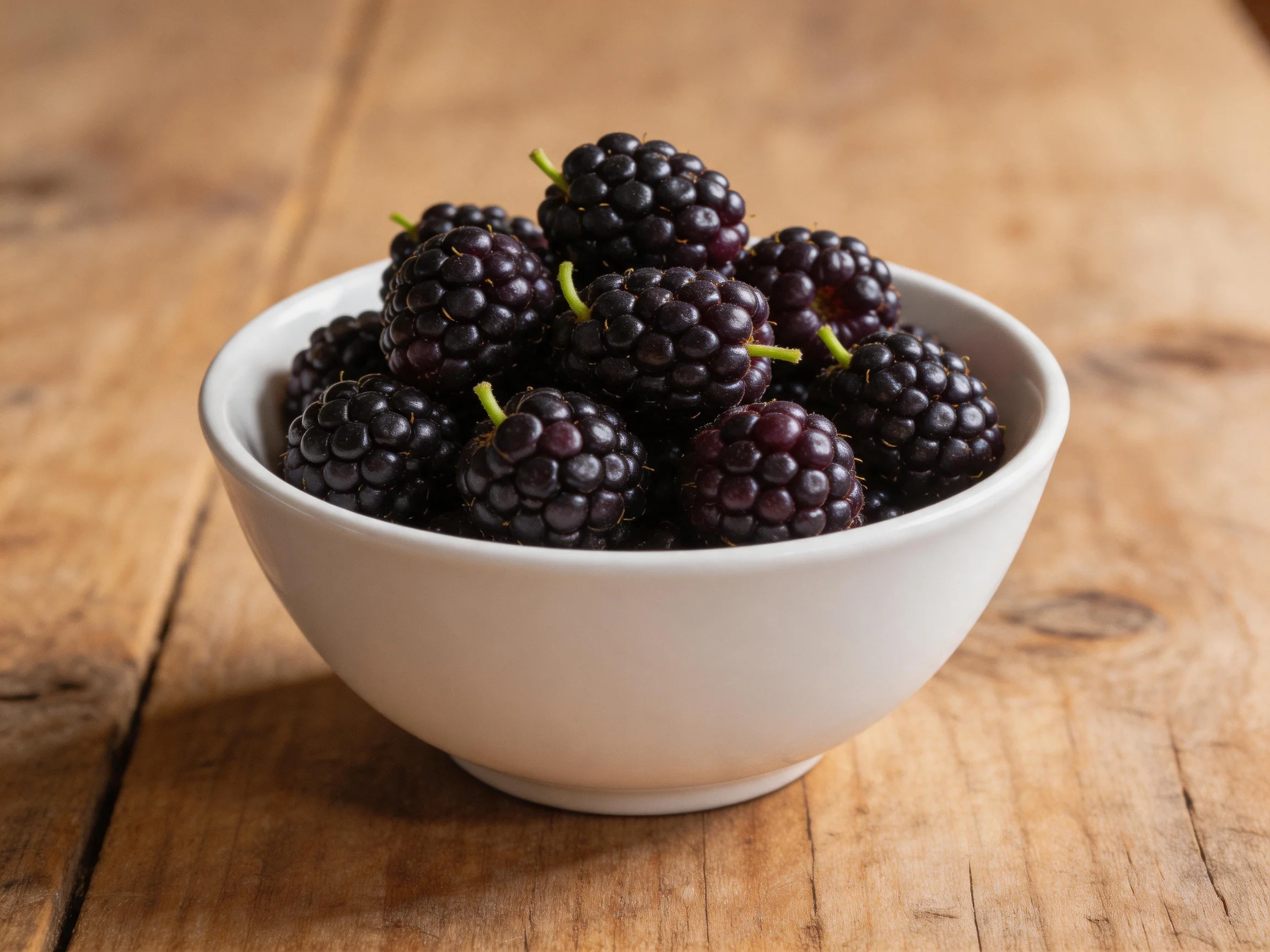 A white bowl brimming with dark purple berries on rustic wood