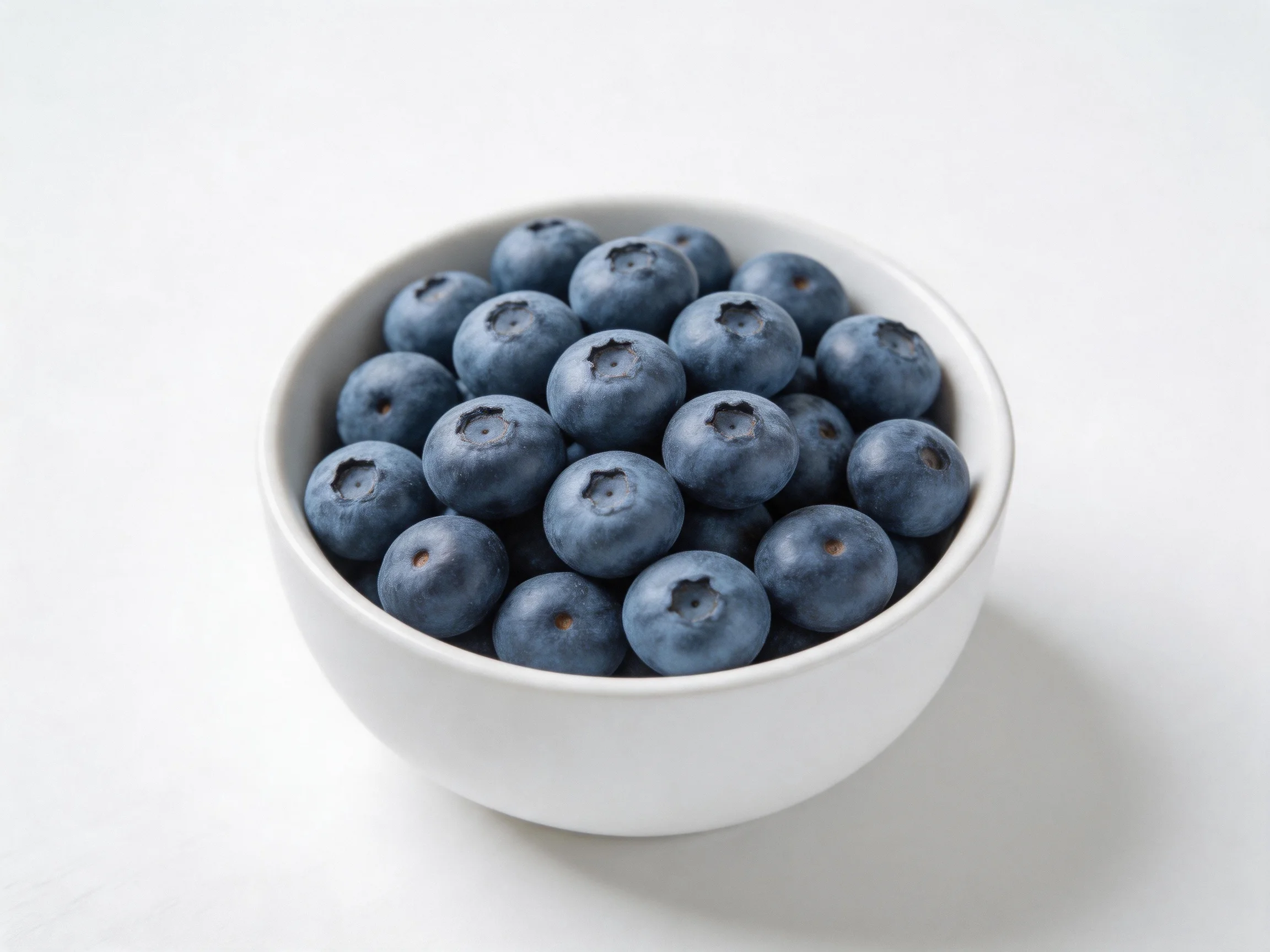 A white bowl overflowing with plump blueberries