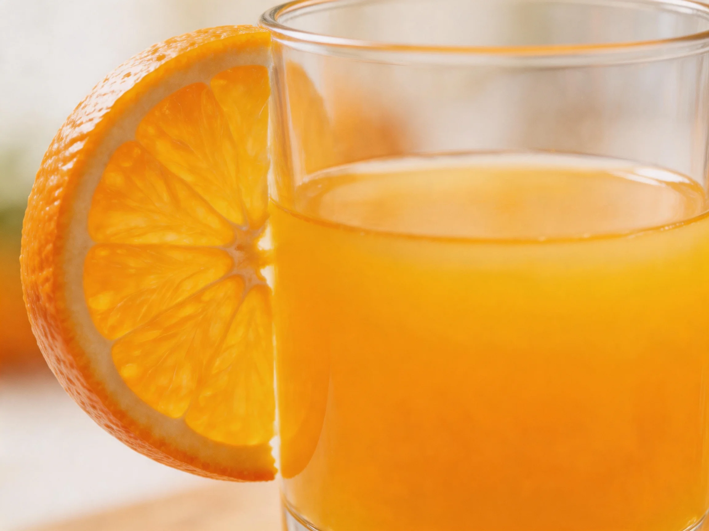 Clear glass filled with orange juice and an orange slice