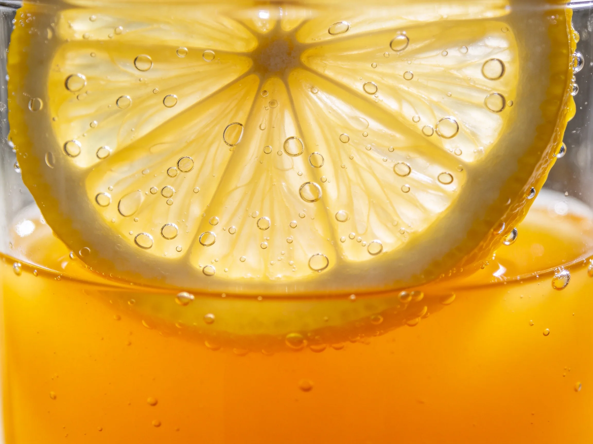 Close-up of a lemon slice in bubbling amber liquid