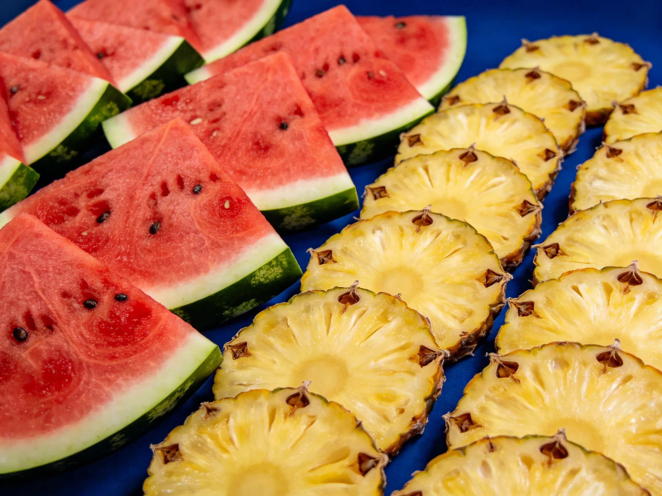 Fresh Watermelon Slices and Pineapple Rings on a Blue Surface