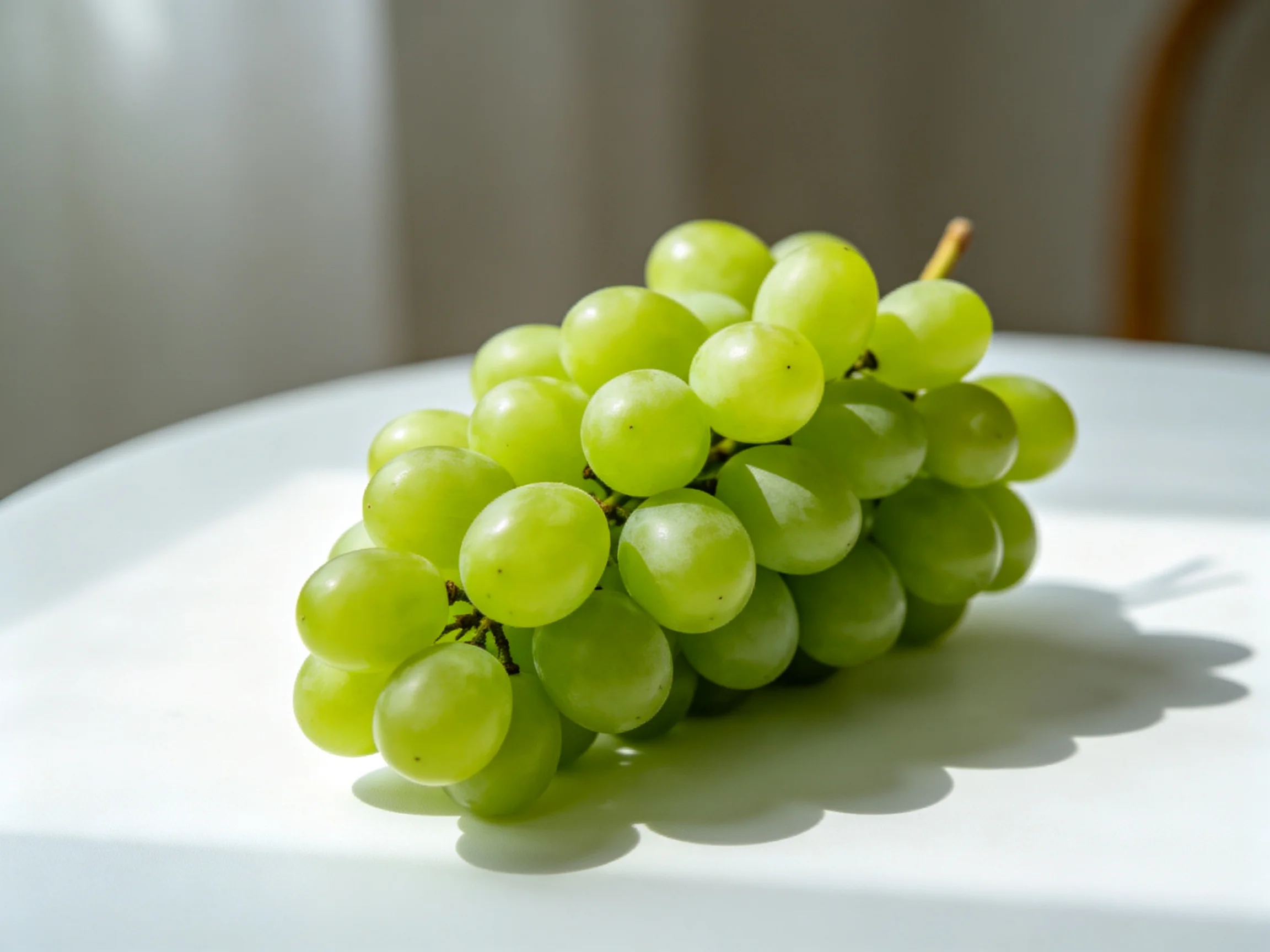 Fresh green grapes clustered on a bright white surface